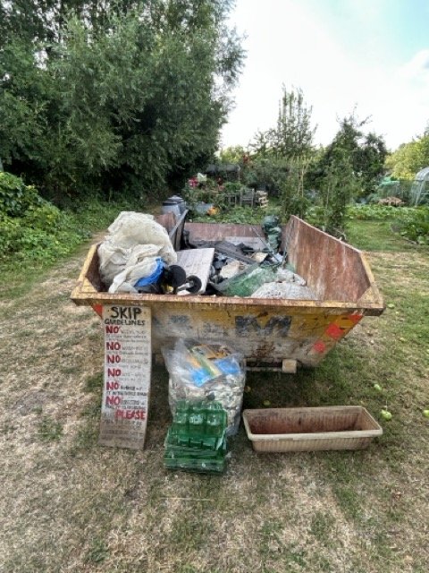 A full skip ready for collection on the allotments to remove inorganic rubbish