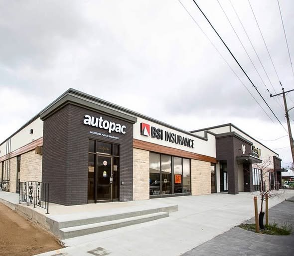 A commercial shopping center with stores, including Autopac and BSI Insurance, situated on a sidewalk with steps leading up to the entrances, under overcast skies.