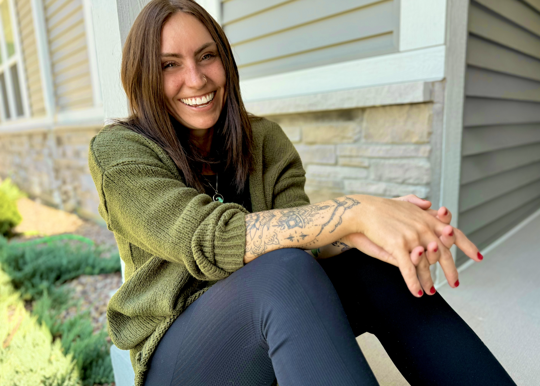 woman sitting on ground casually with a smile and laughing