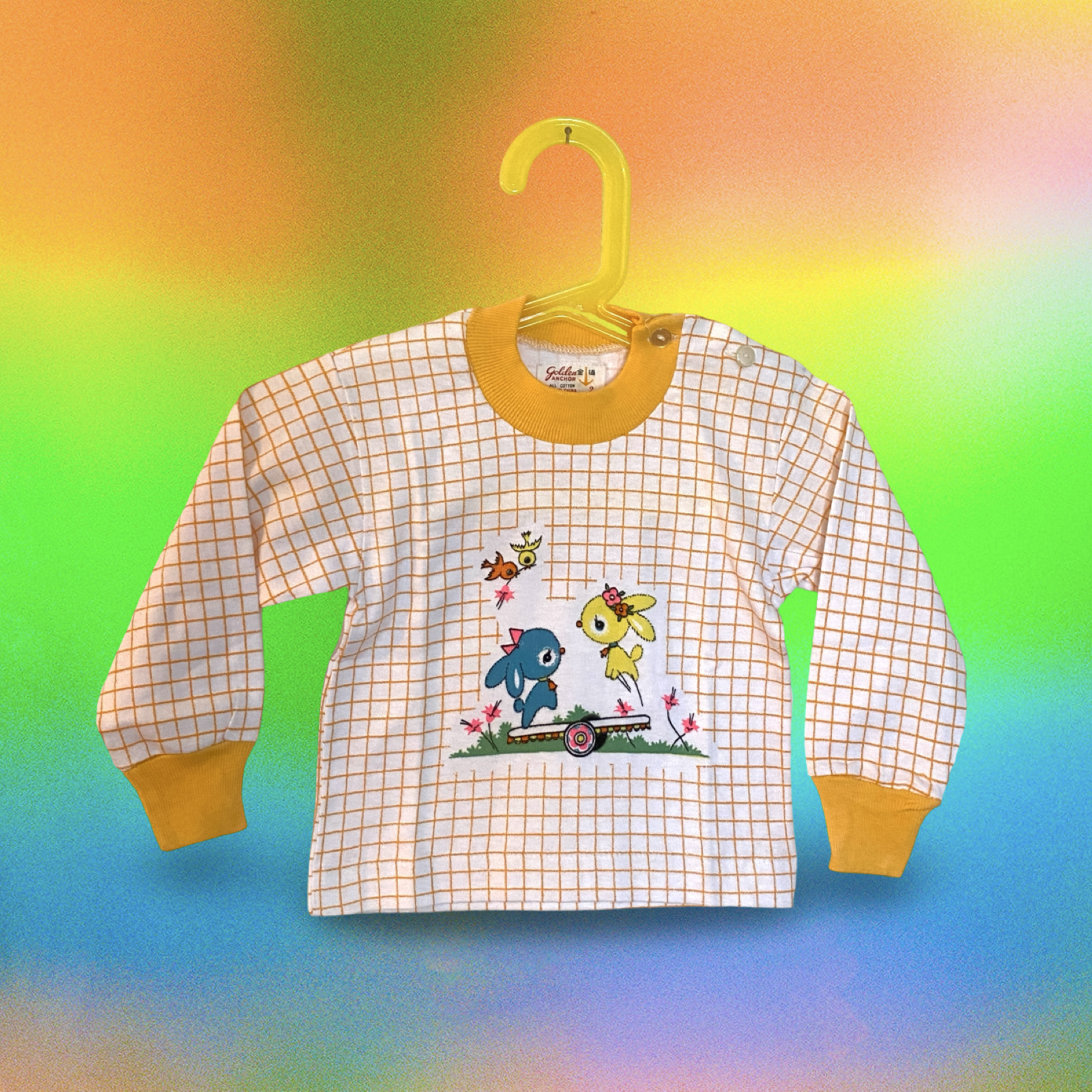 Vintage 1960s Children's long-sleeve shirt with orange checkered pattern, yellow collar and cuffs, featuring a cartoon bunny on a skateboard with three colorful birds and flowers.