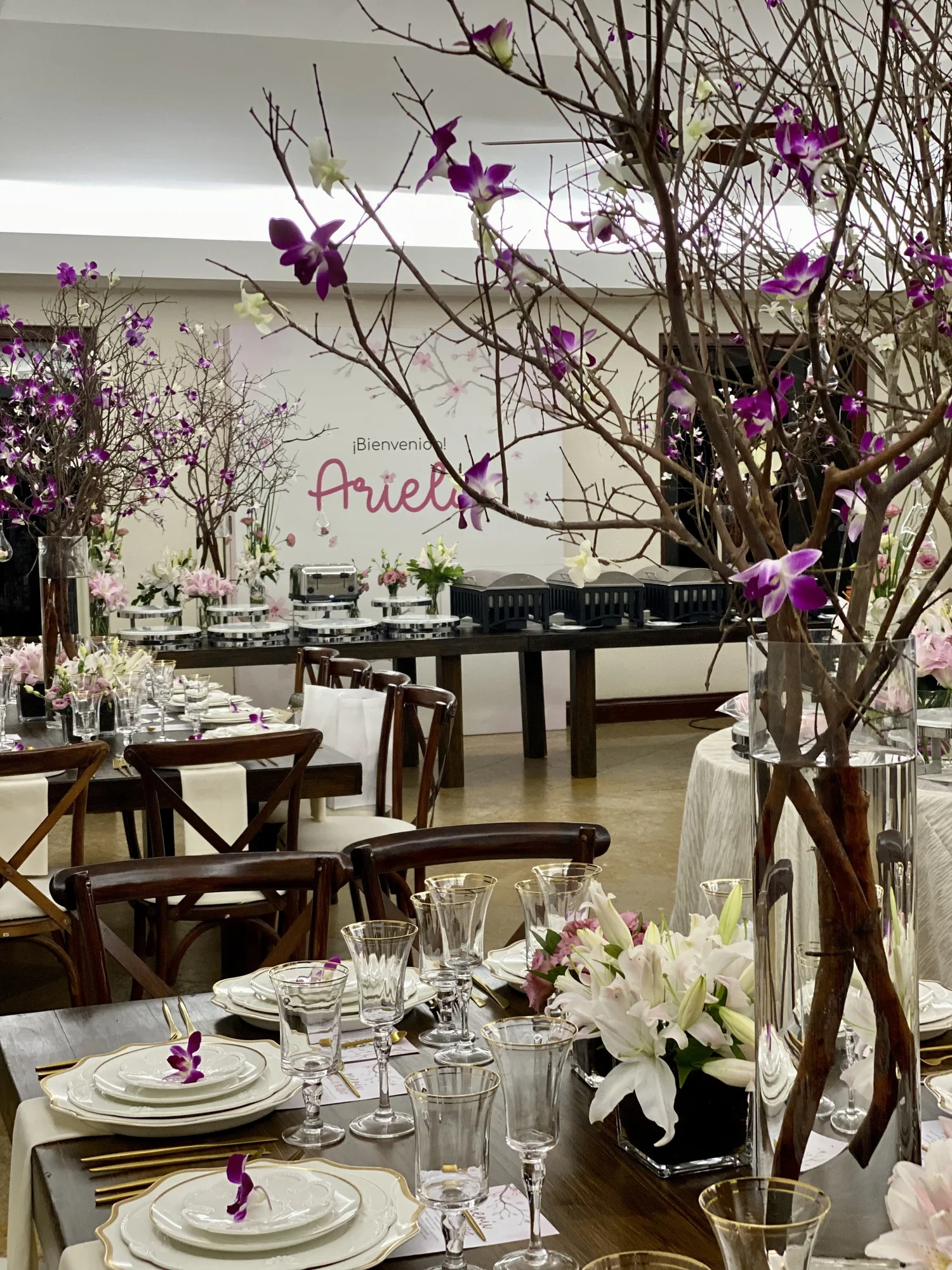 Salón con ramas de cerezo en flor y el nombre Ariela en neón al fondo
