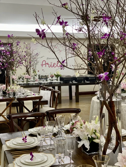 Salón con ramas de cerezo en flor y el nombre Ariela en neón al fondo