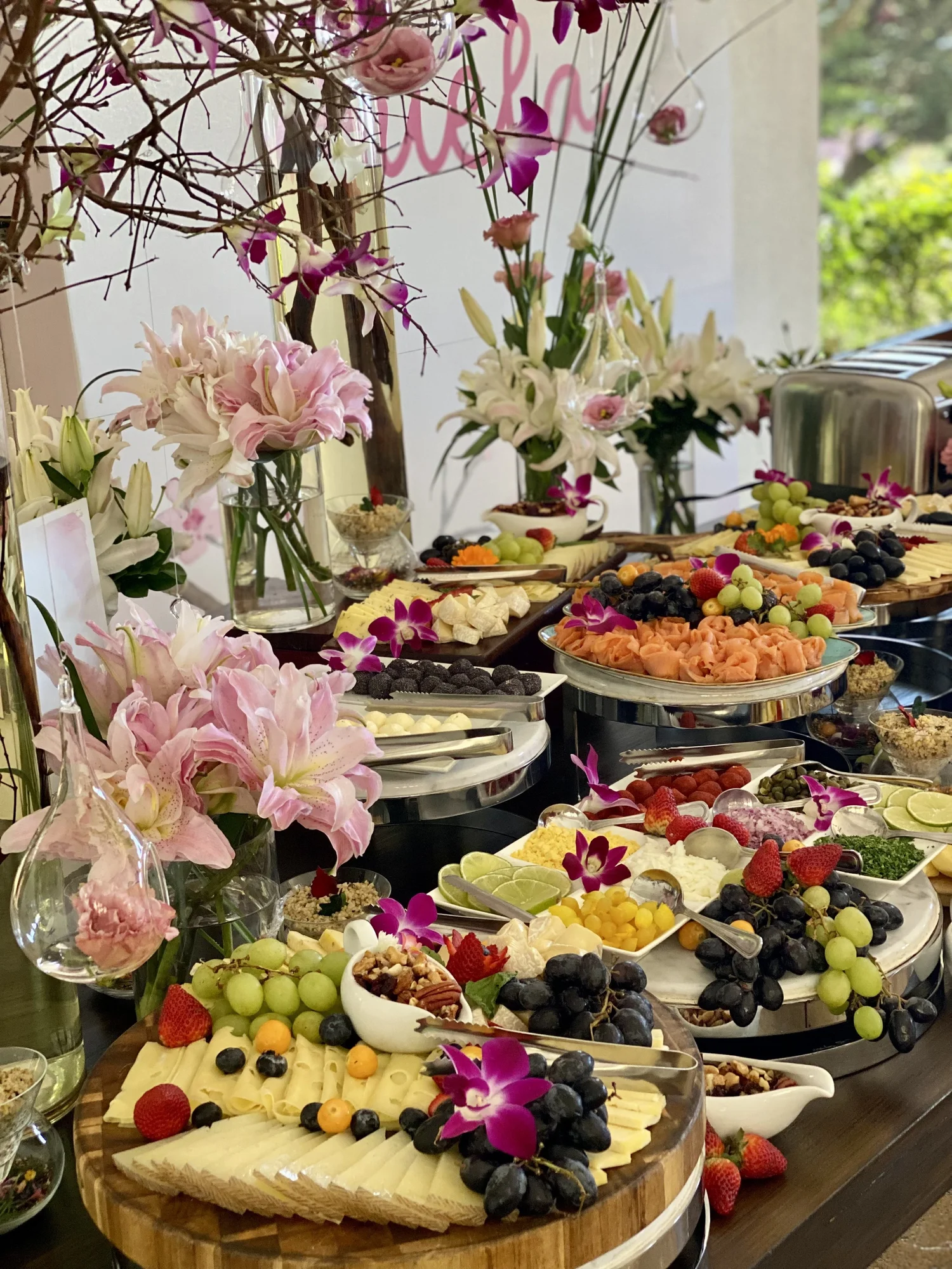Mesa de buffet con frutas y lirios rosados