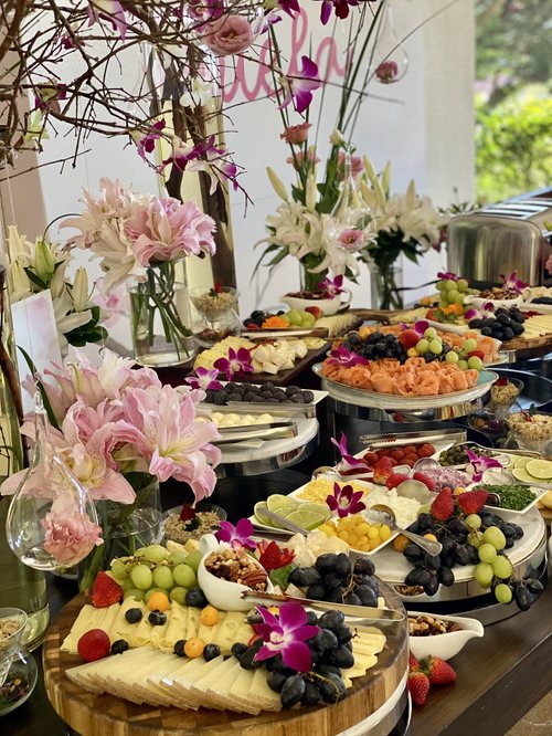 Mesa de buffet con frutas y lirios rosados