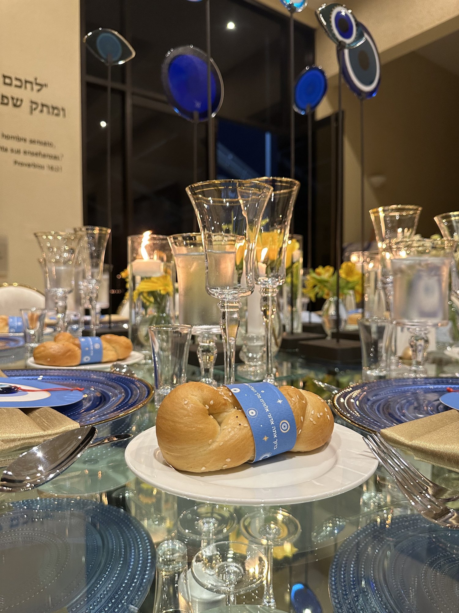 Centro de mesa con flores amarillas, velas y ojos de vidrio azul
