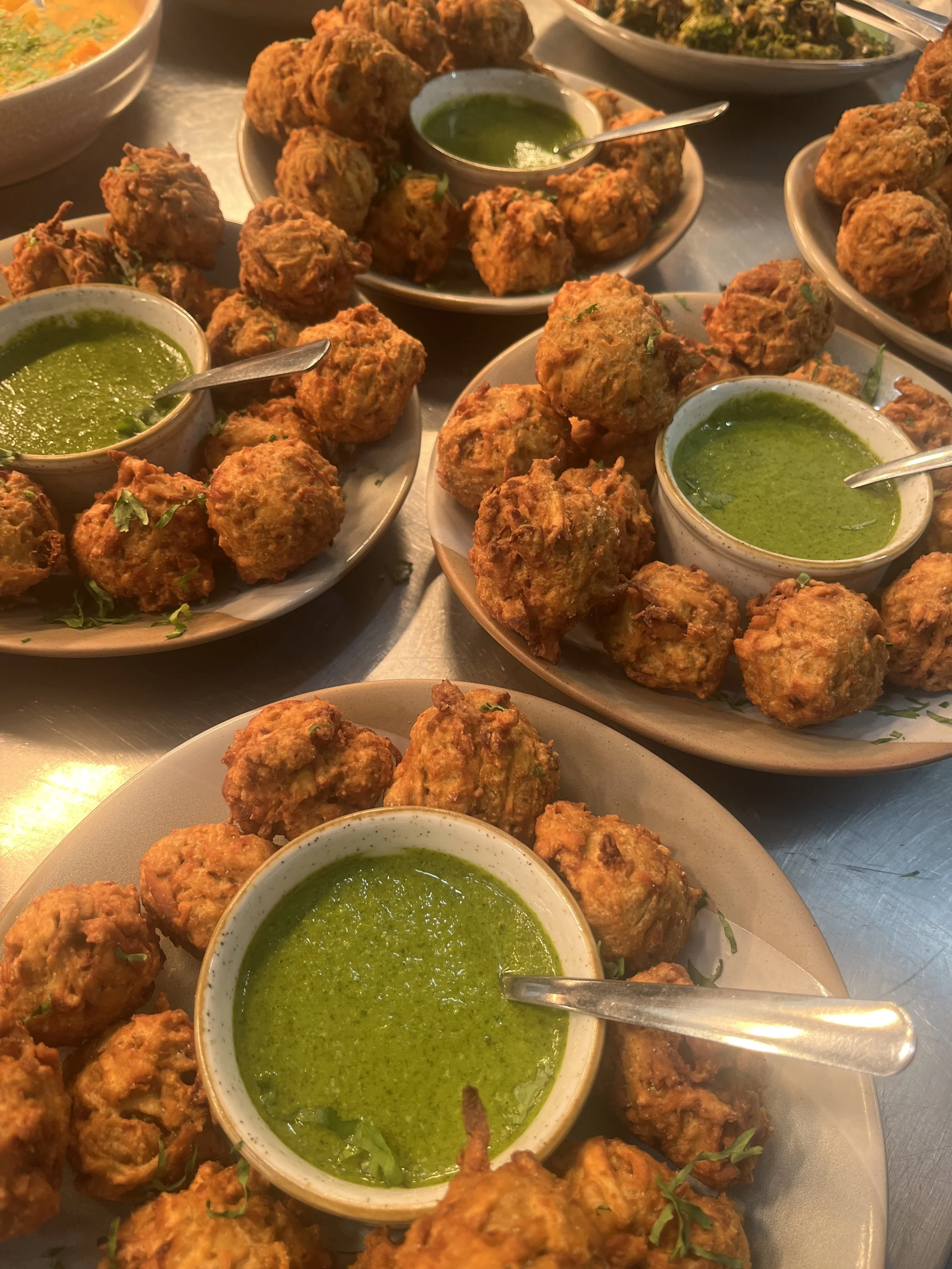 Plate of Indian vegetable cutlets served with green chutney, garnished with chopped herbs.