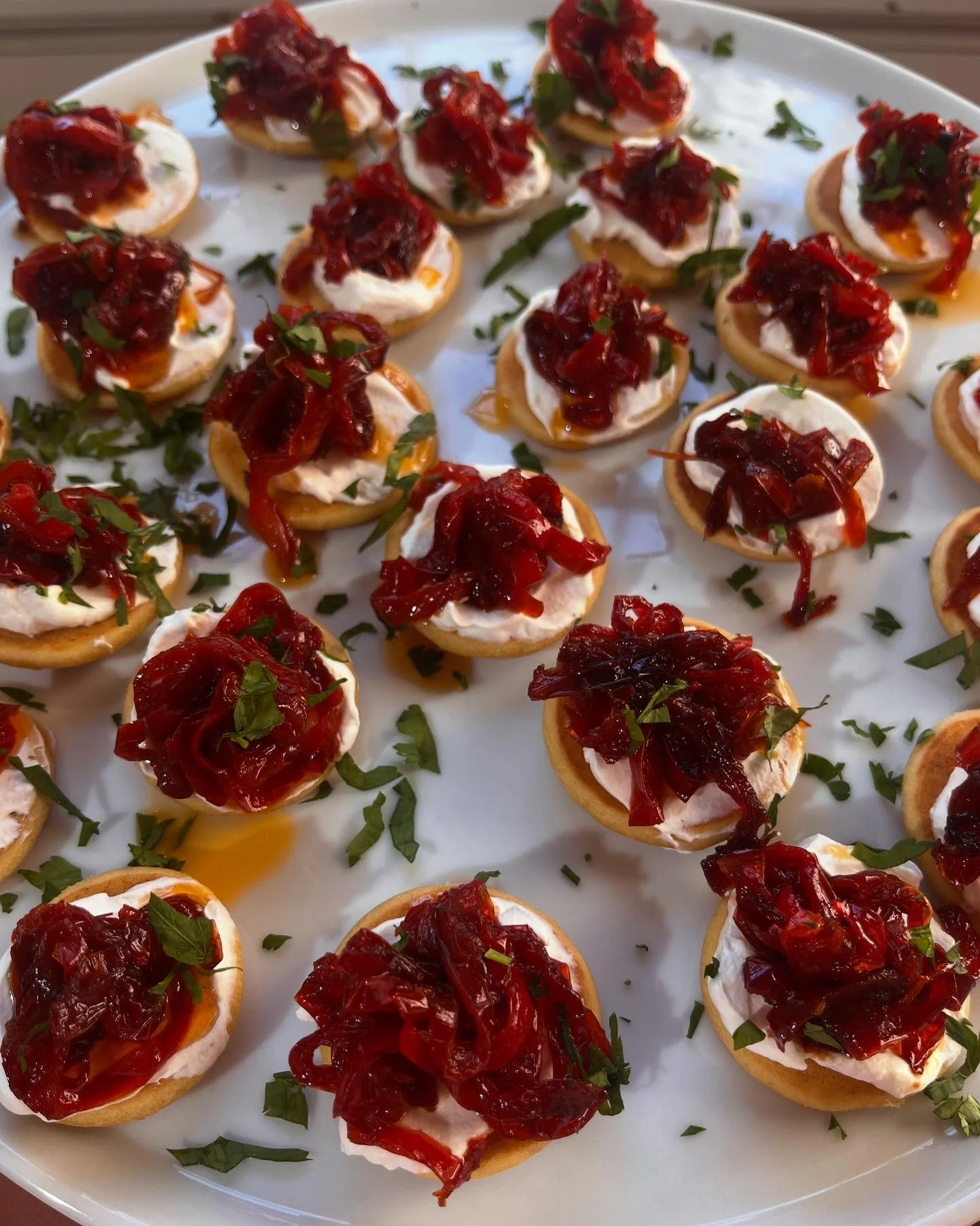 Tray of appetizer bites with crackers, whipped cheese, caramelized onions, and chopped herbs.
