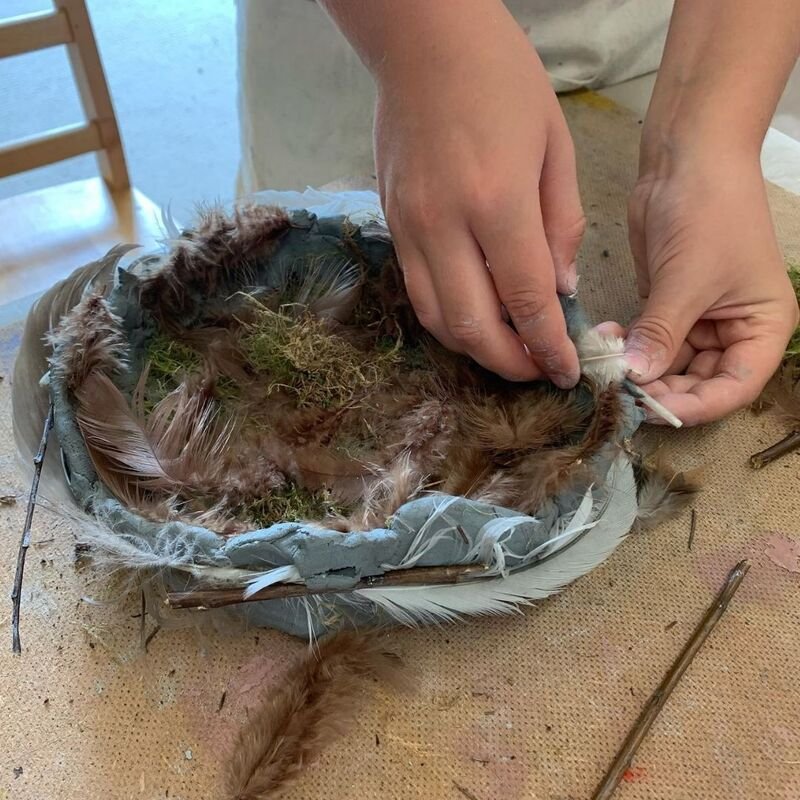 A child creating a moss and feathered bowl.