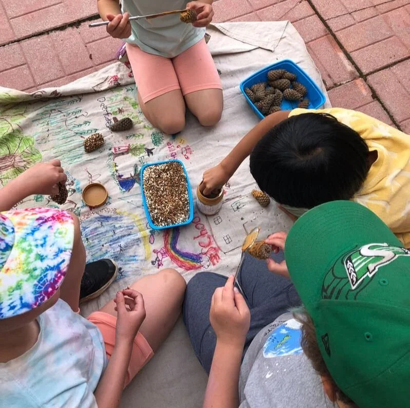 Four children are sitting on a blanket on a brick patio.