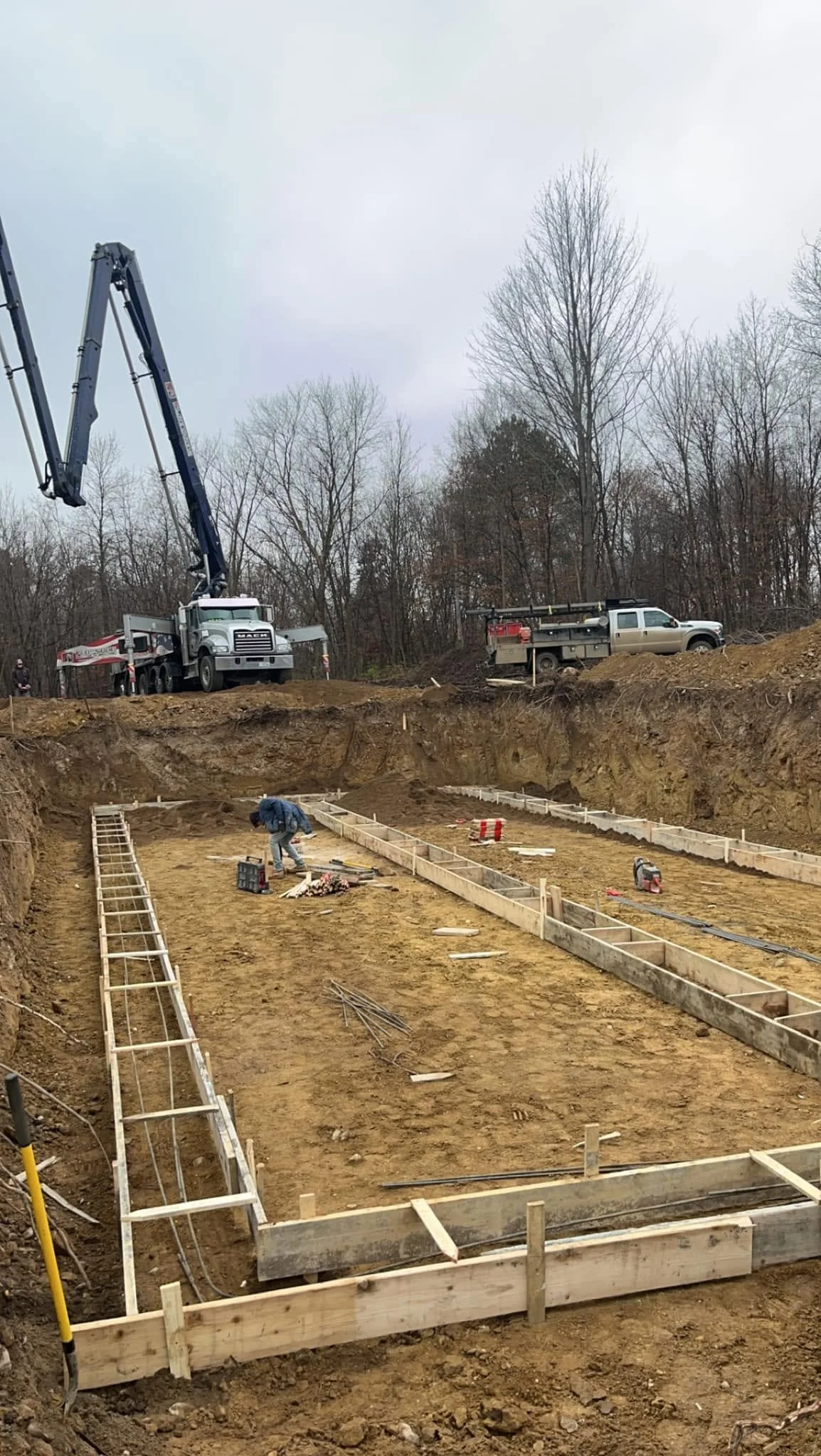 Construction site with workers and machinery preparing foundation for a building.