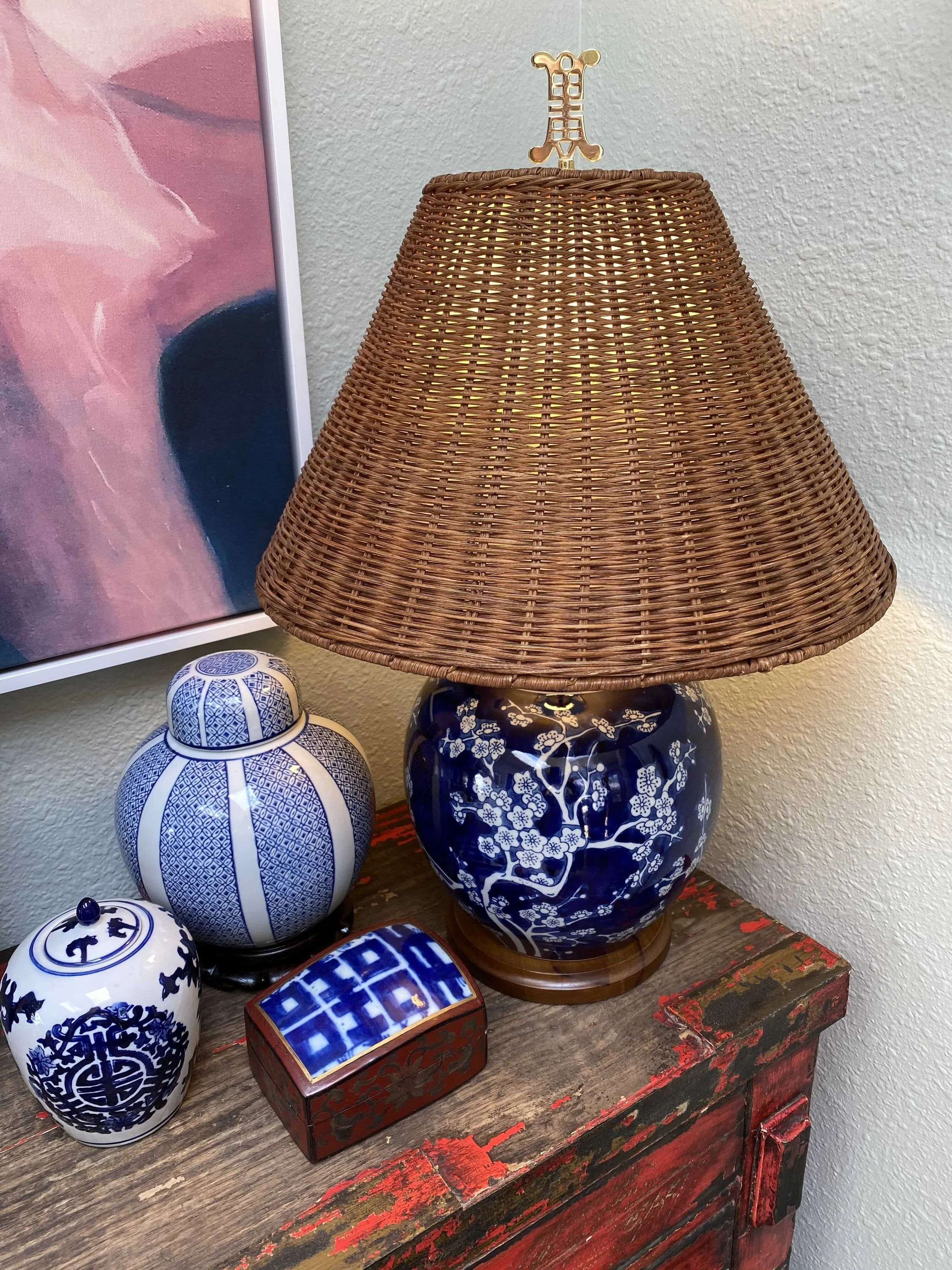 Decorative blue and white porcelain vases, a wooden table with an antique red finish, a blue with white pattern table lamp, and a rectangular blue and white patterned box.