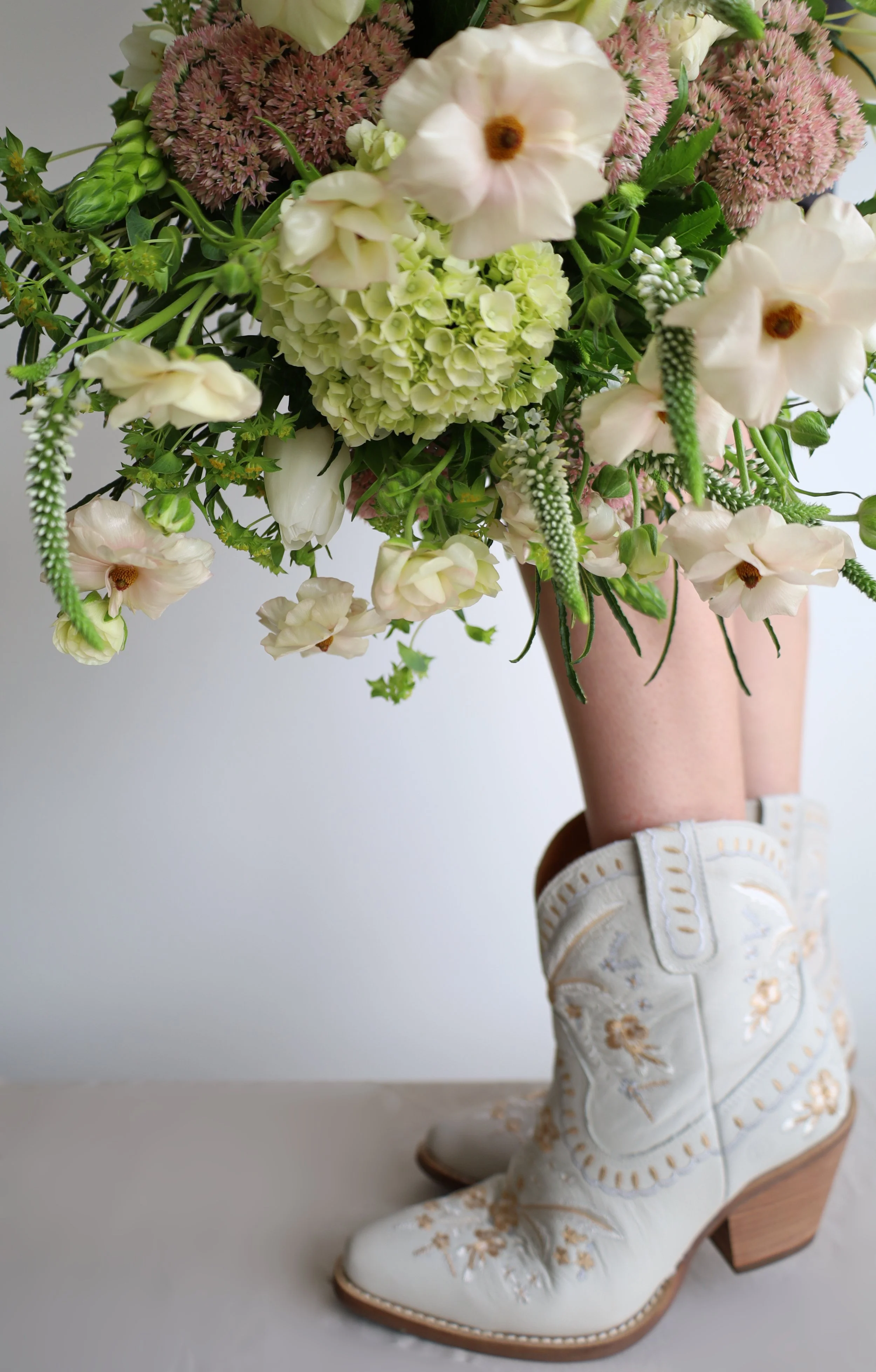 Close-up of a flower bouquet and white embroidered boots.