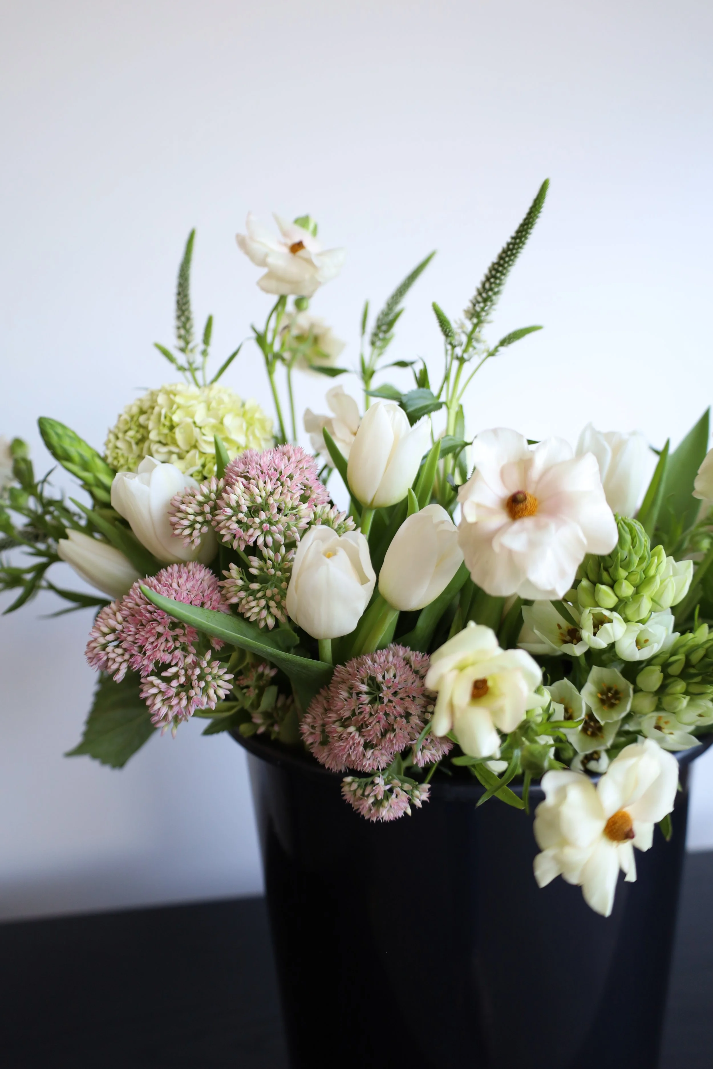 Flowers in a black bucket against a white background.