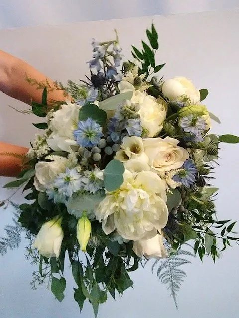 A bouquet of white and light purple flowers with green foliage.