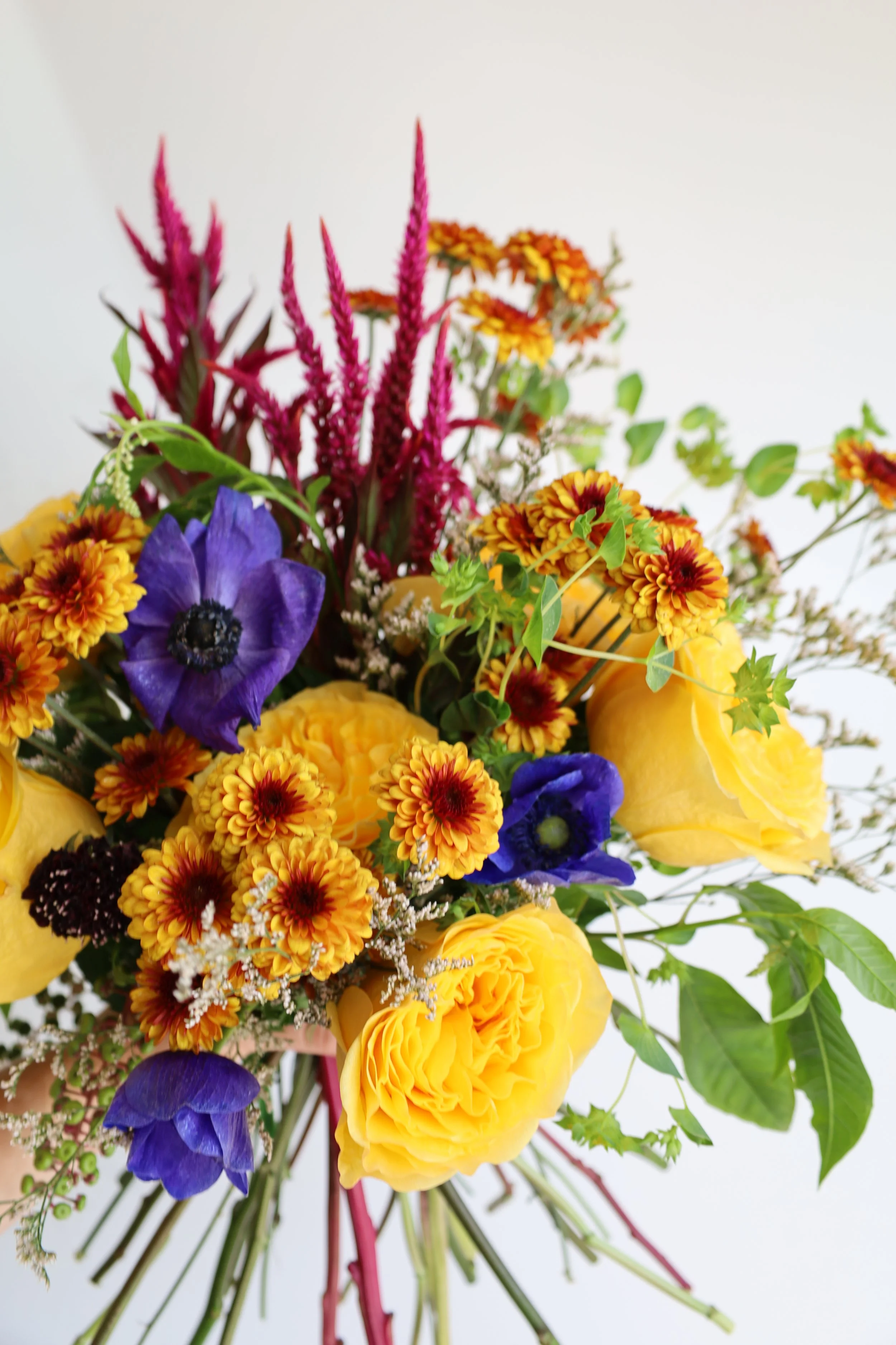 A colorful bouquet of flowers with yellow, purple, orange, and pink blossoms.