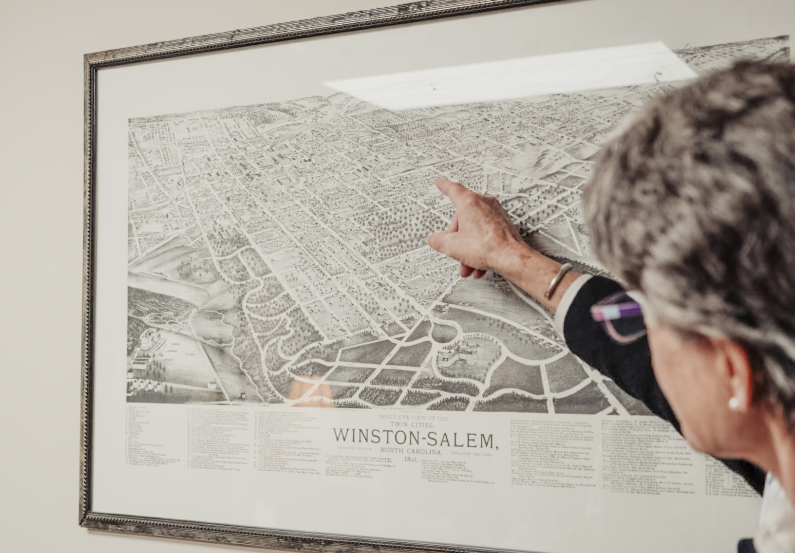 Person pointing to a framed historical bird’s-eye map of Winston-Salem, North Carolina.