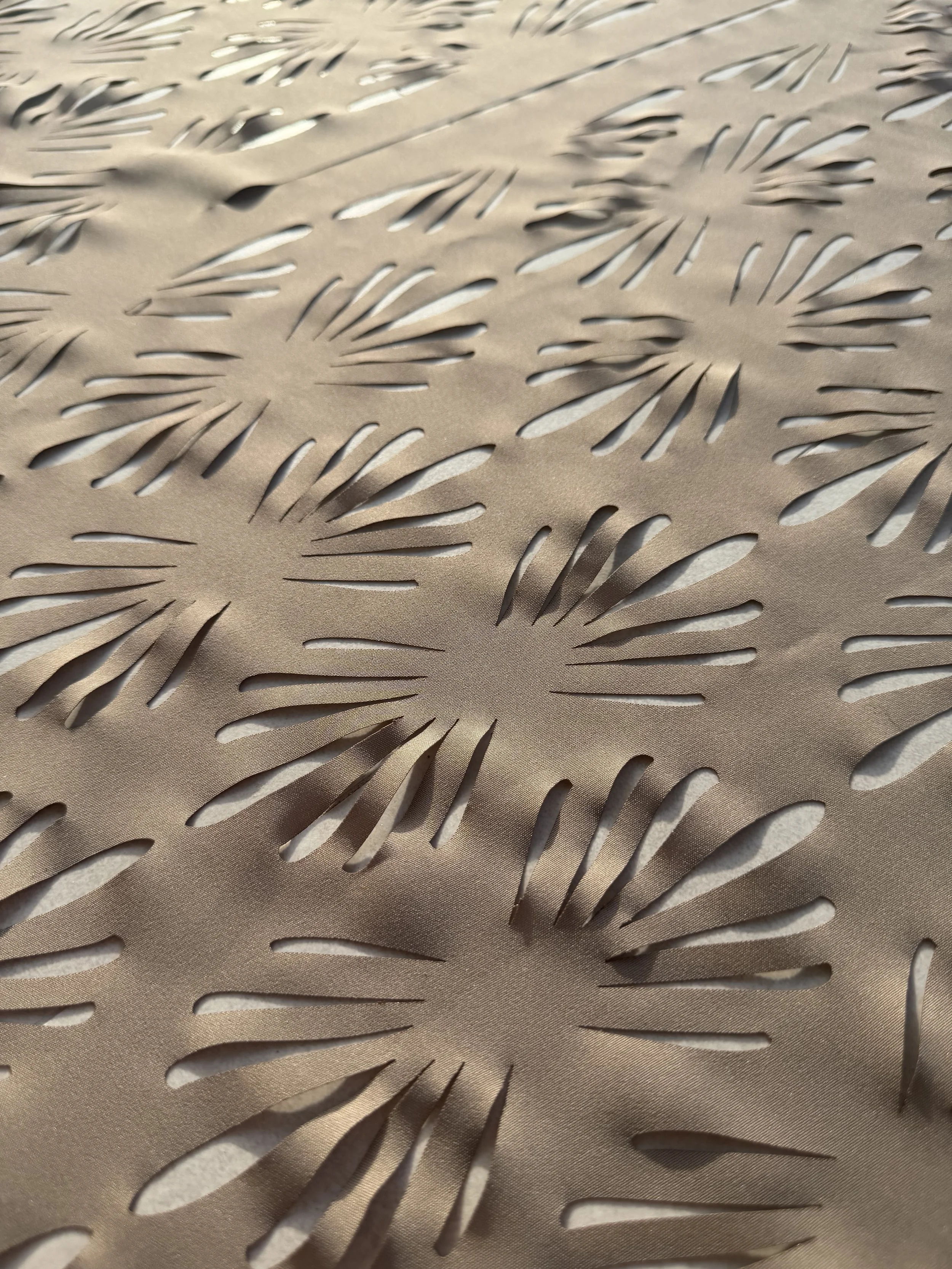 Close-up of a metallic surface with a pattern of leaf-shaped cut-outs.