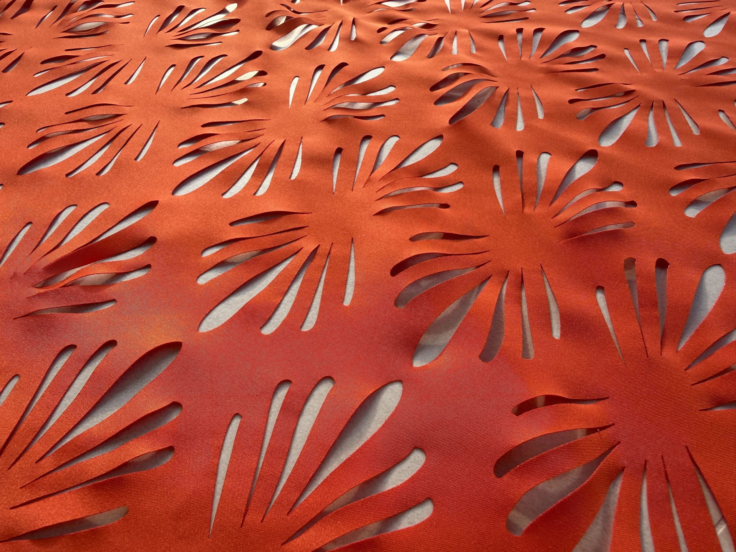 Close-up view of a decorative orange paper with cut-out patterns resembling palm leaves or floral shapes.