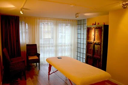 Warme woonkamer met lange eettafel, stoelen, vitrinekast, gordijnen en glazen wand
