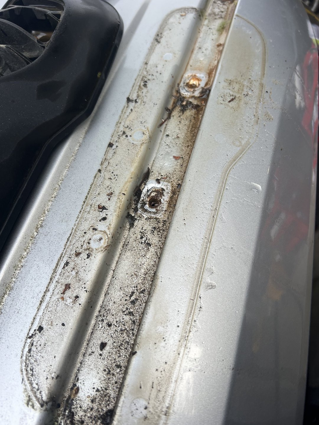 Rear-body water-leak diagnosis — Contamination exposed behind trim near the body seam.