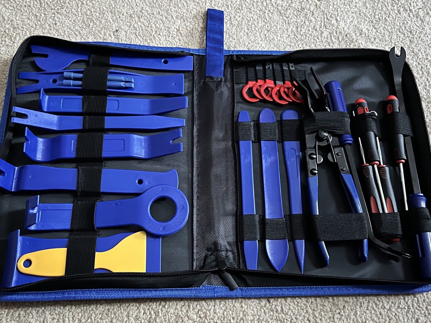 Open black case with blue tools, including prying tools, screwdrivers, and other repair tools arranged with elastic straps.
