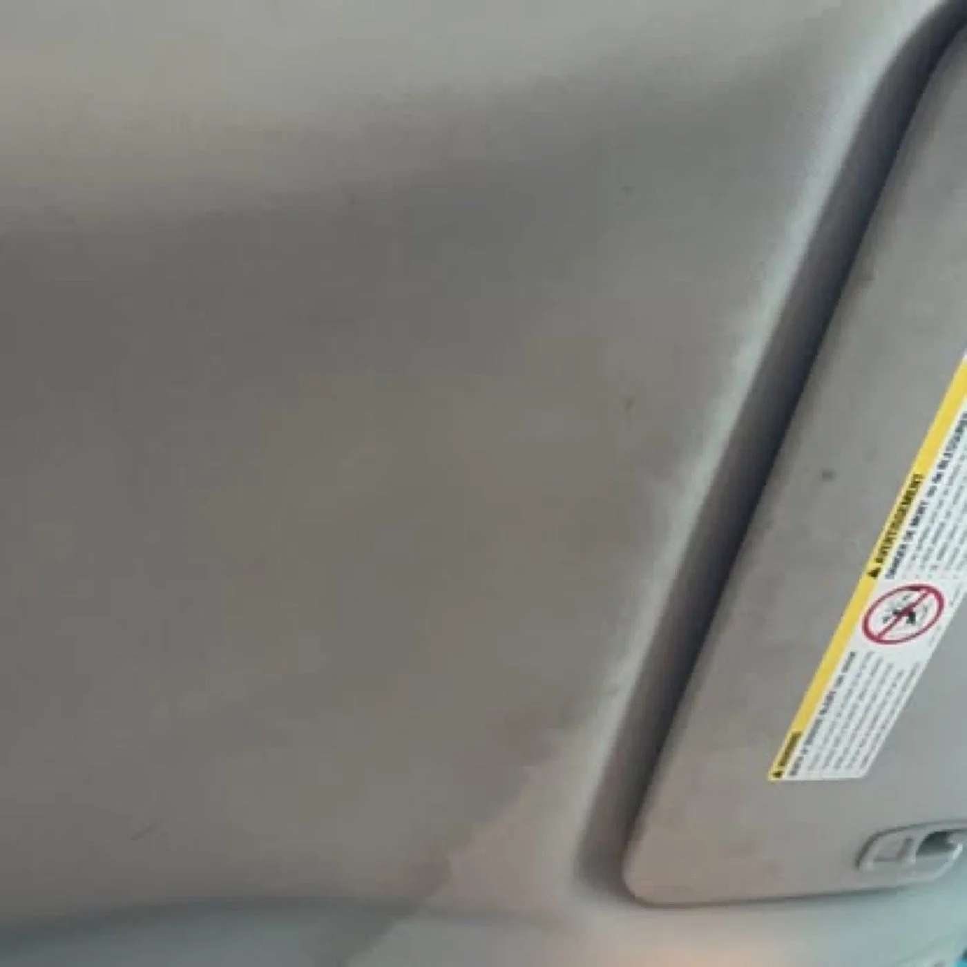 Close-up of a vehicle body component and warning label inspected during automotive leak diagnosis.