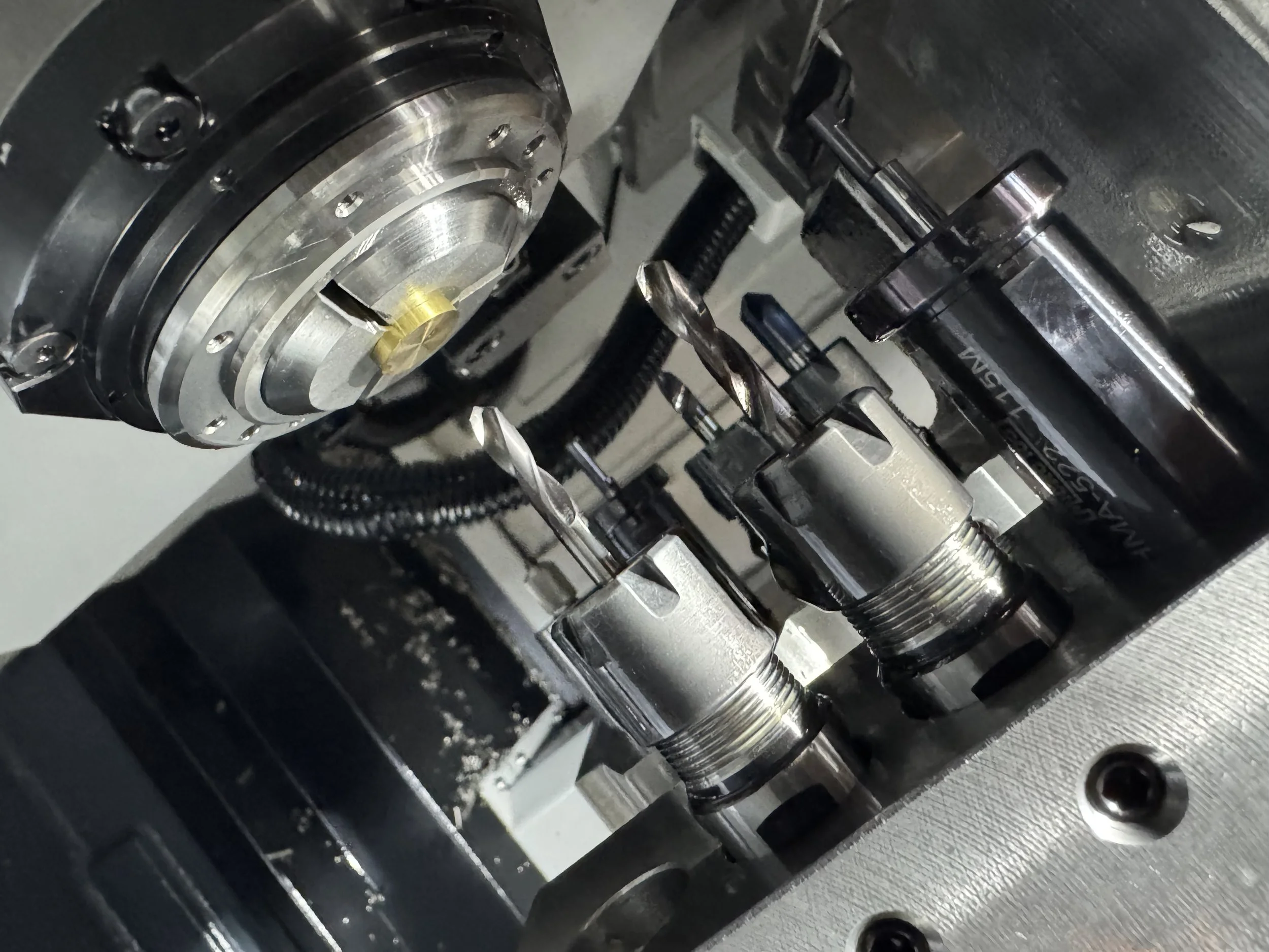 Close-up of the internal components of a Swiss lathe that is set up with tools to cut metal and plastic. .