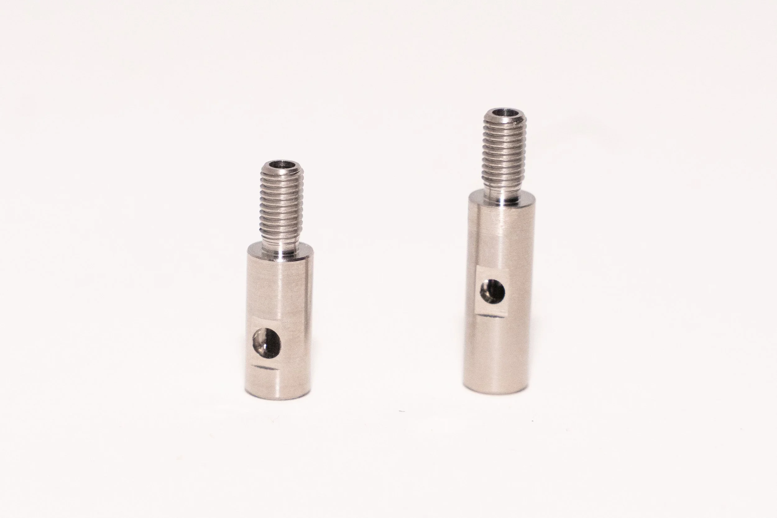 Two precision machined metal components with threaded sections and holes, photographed against a plain white background.