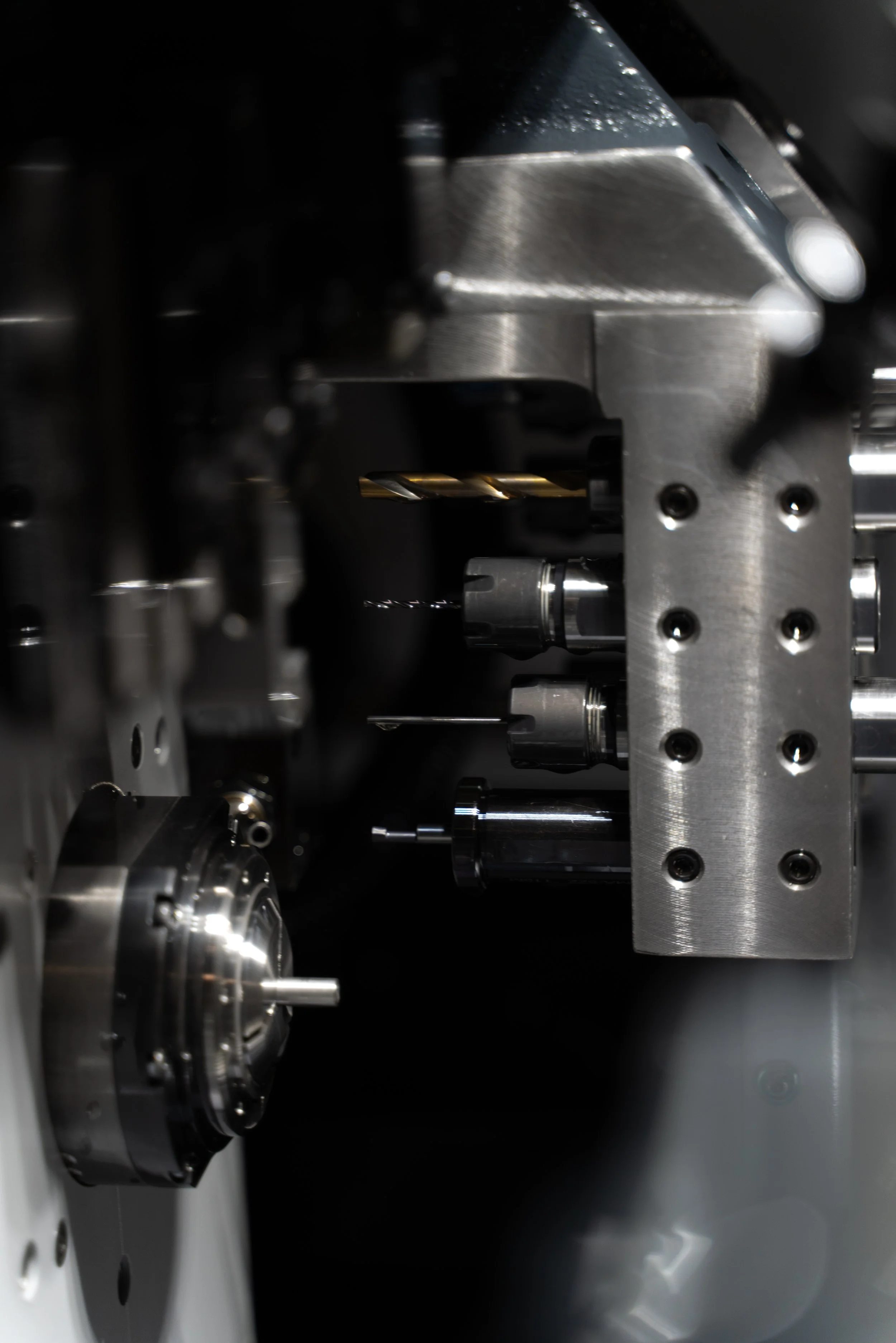 Close-up view of a complex metal mechanical apparatus with various screws, blades, and cylindrical components, likely part of a precision machine or industrial equipment.