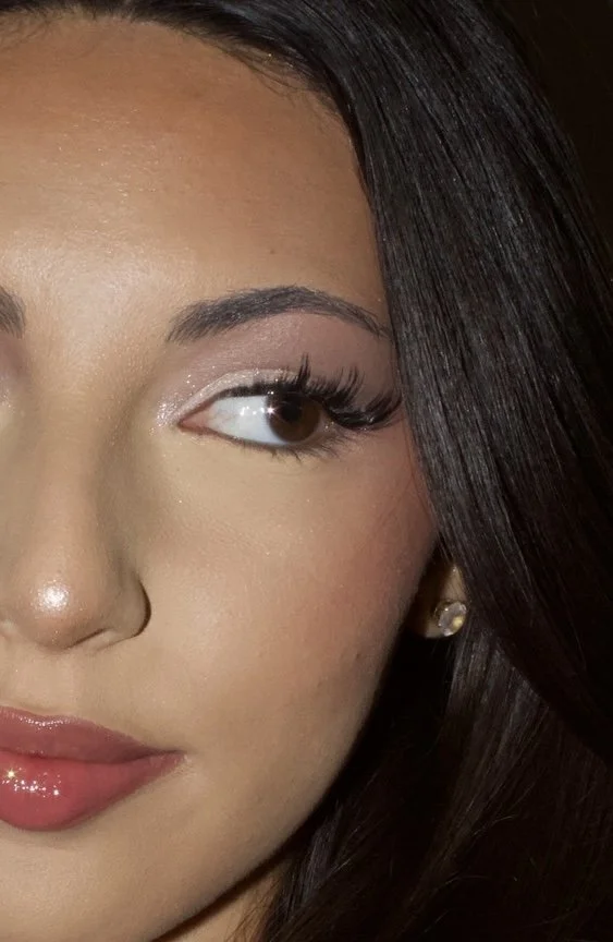 Close-up of a woman's face showing her eye, eyebrow, and lips, with dark hair partially covering her cheek.