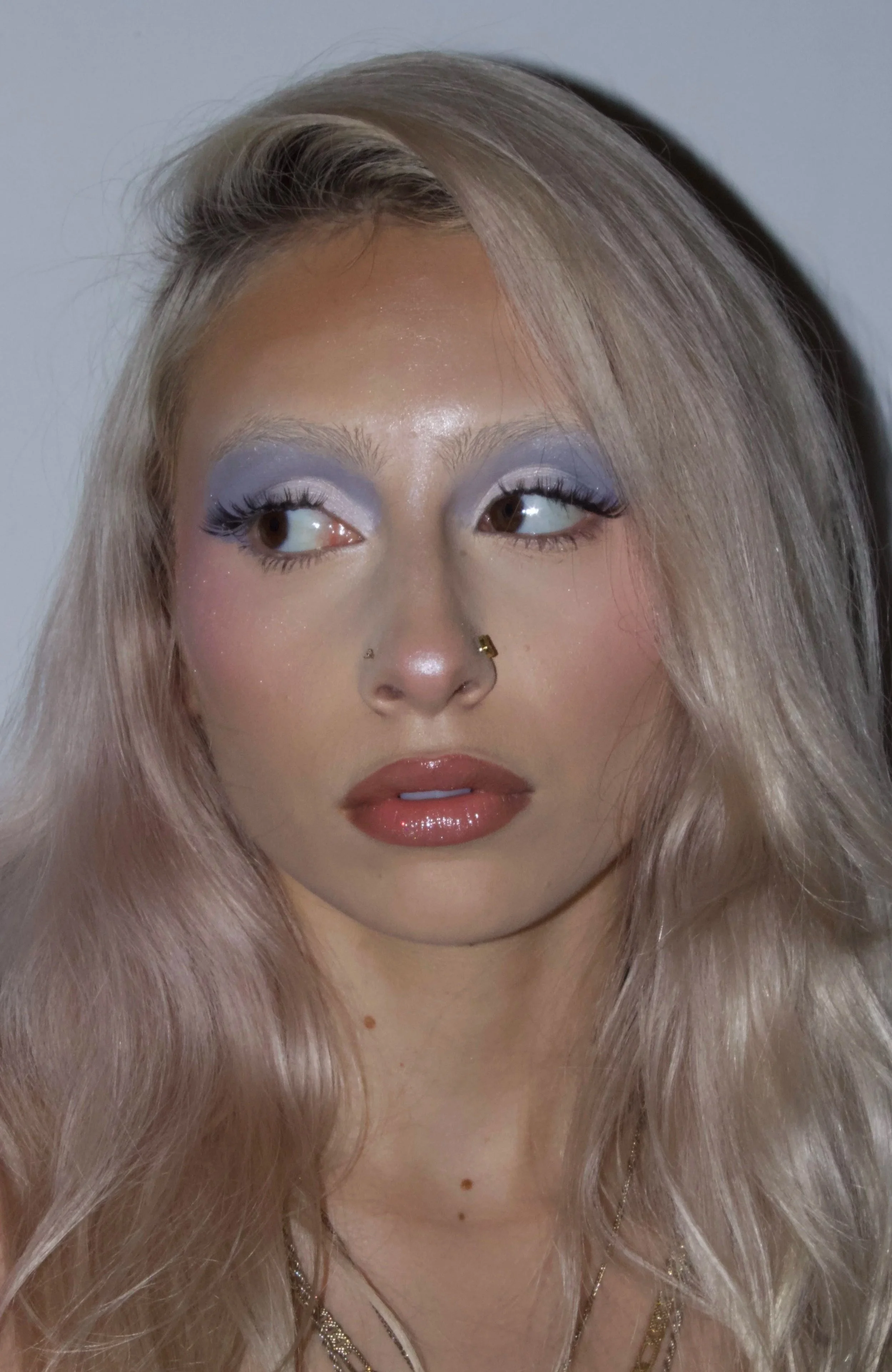 Close-up of a woman with platinum blonde hair and makeup, looking to the right.