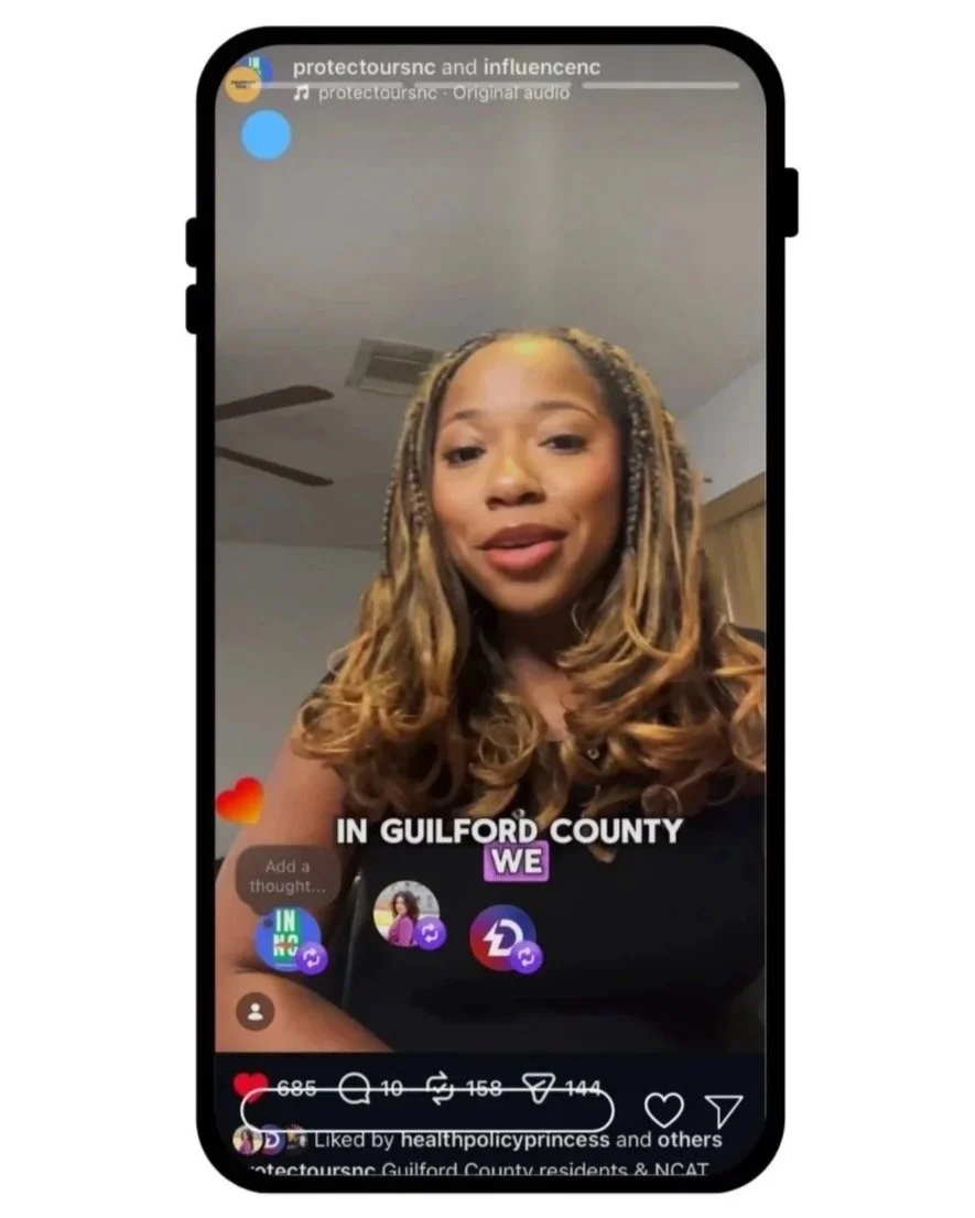 A woman with long, styled hair speaking in a video on a smartphone screen during a live Instagram session, with text overlay saying "IN GUILFORD COUNTY WE" and icons indicating likes and comments.