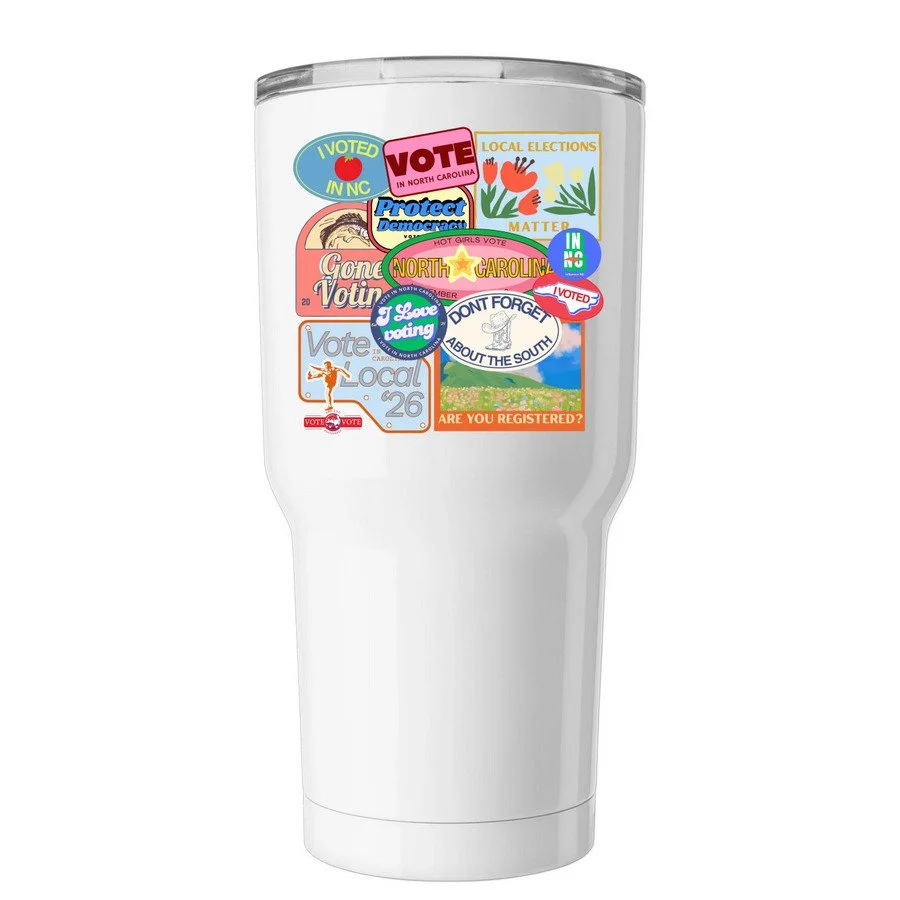 A white tumbler covered with various stickers promoting voting and local elections in North Carolina.