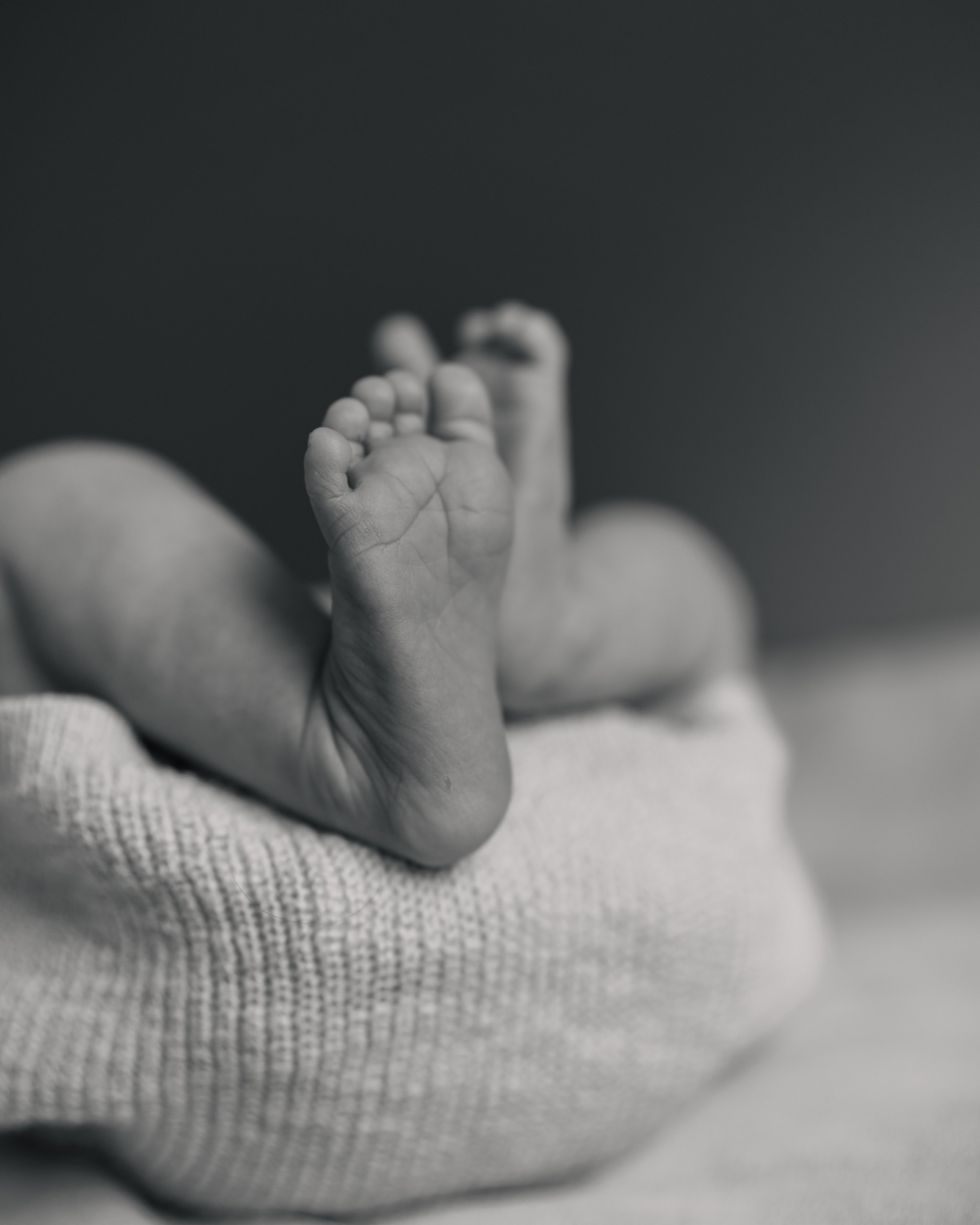 Nahaufnahme eines Babyfußes auf einem weichen, hellgrauen Tuch.