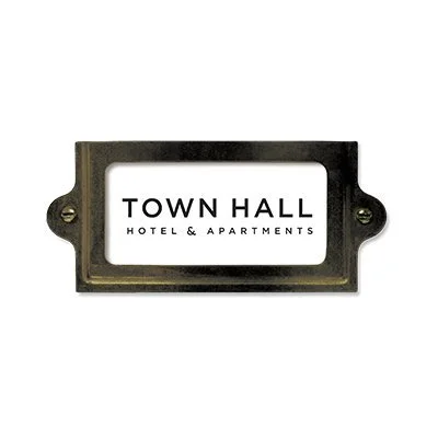 A sign with the text "Town Hall Hotel & Apartments" in black letters on a white background, mounted on a black metal frame.