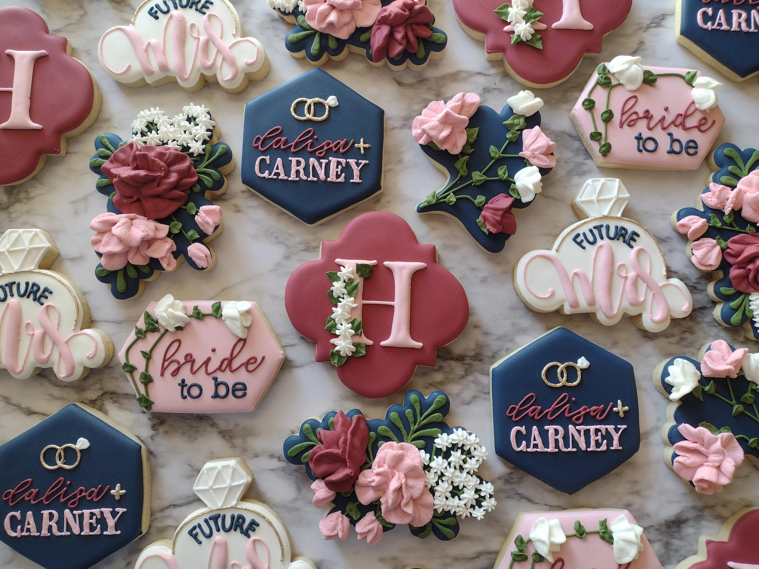 Decorative cookies with bridal shower messages, including 'Bride to be', and 'Future Mrs'. Cookies are decorated with flowers, rings, hearts, and other wedding-themed designs in pink, blue, white, and green colors.