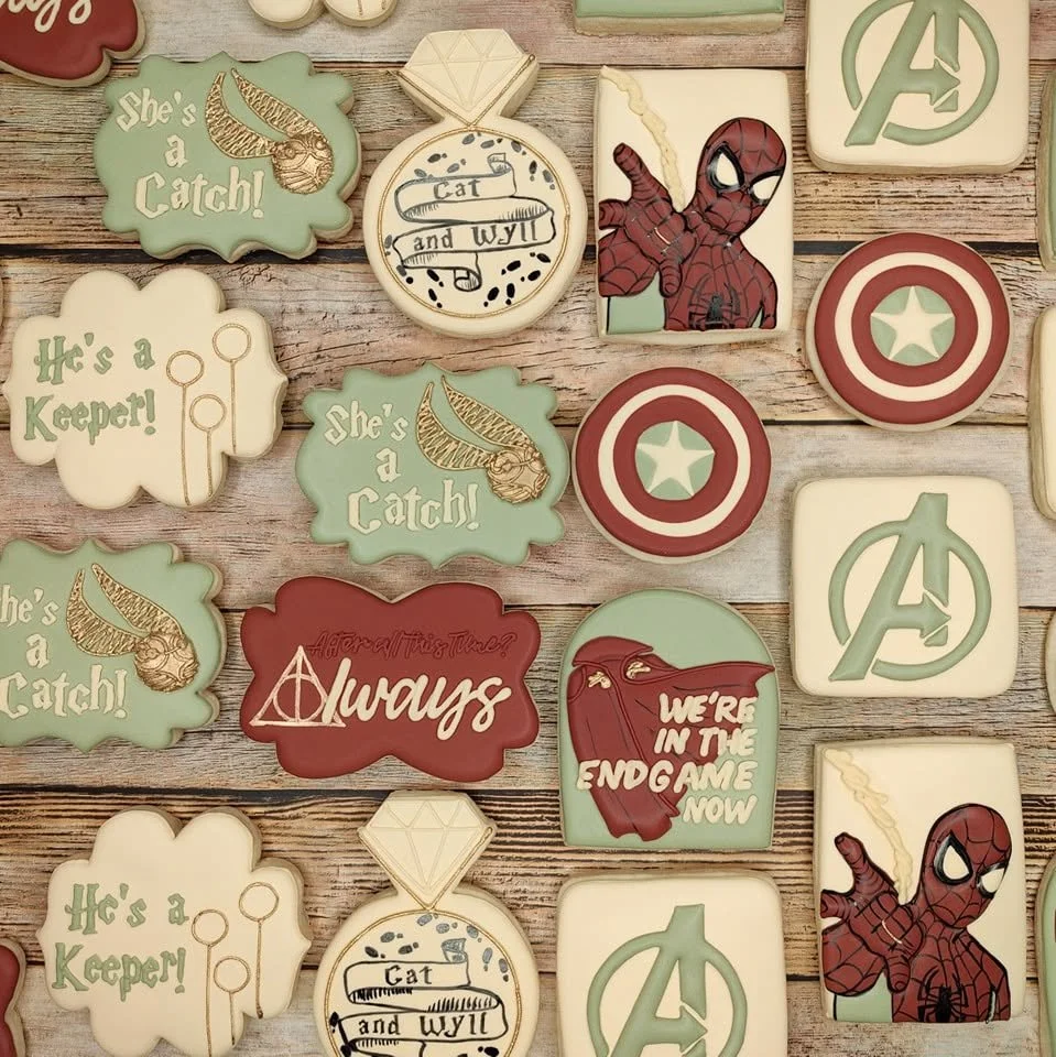 Collection of cookies featuring Marvel Avengers and Harry Potter themes, including Spider-Man, Captain America, Avengers logo, and phrases like "He's a Catch!", "He's a Keeper!", and "Always".