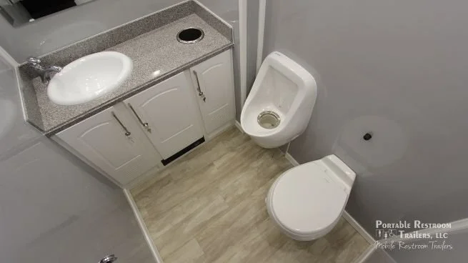 Small restroom with a white sink, gray countertop, white cabinets, a urinal, and a toilet.