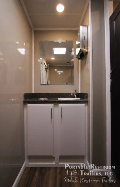 Small bathroom with white cabinet under black countertop, mirror, wall-mounted soap dispenser, and ceiling light.