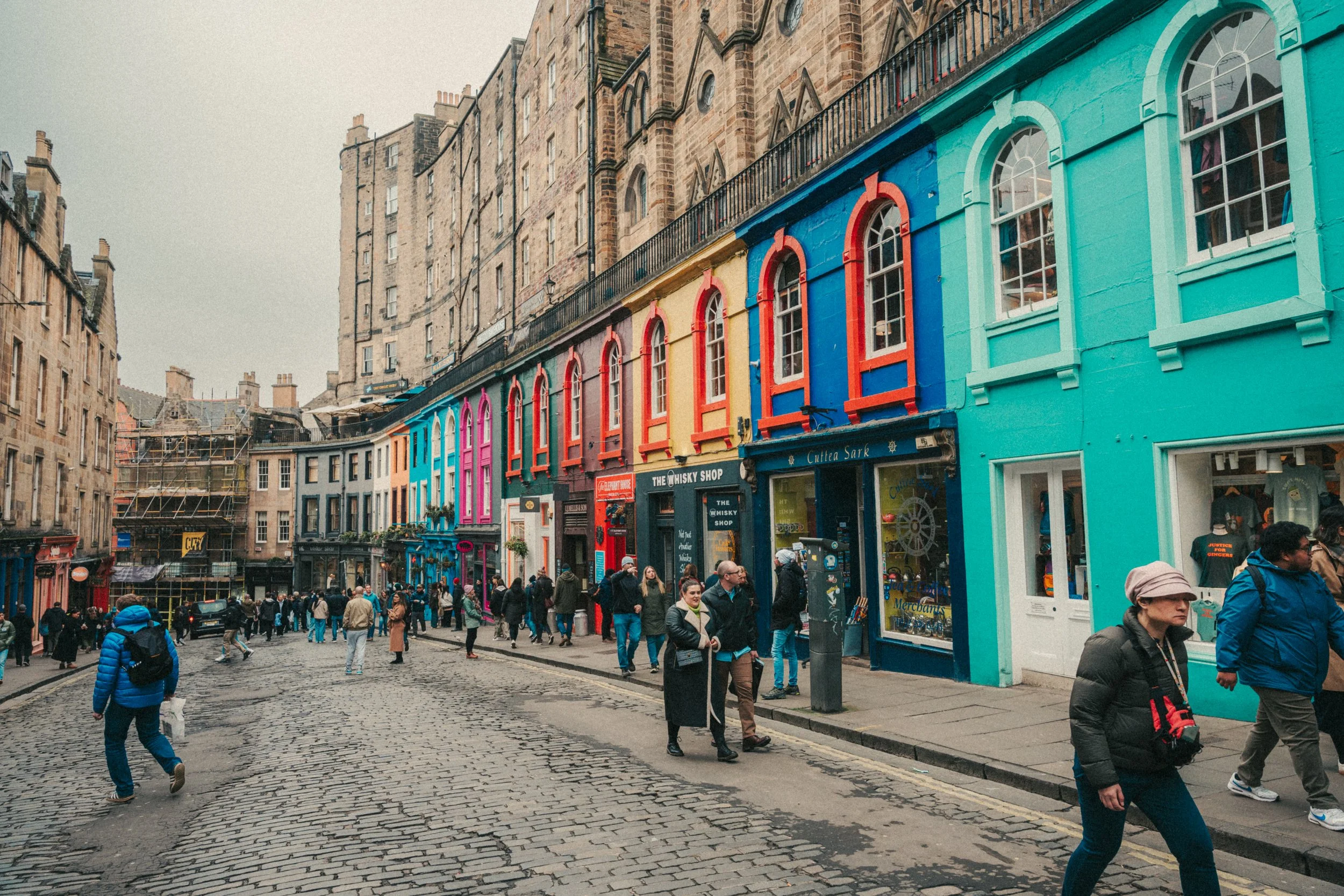 Busy street scene with colorful buildings and pedestrians walking on cobblestone street.