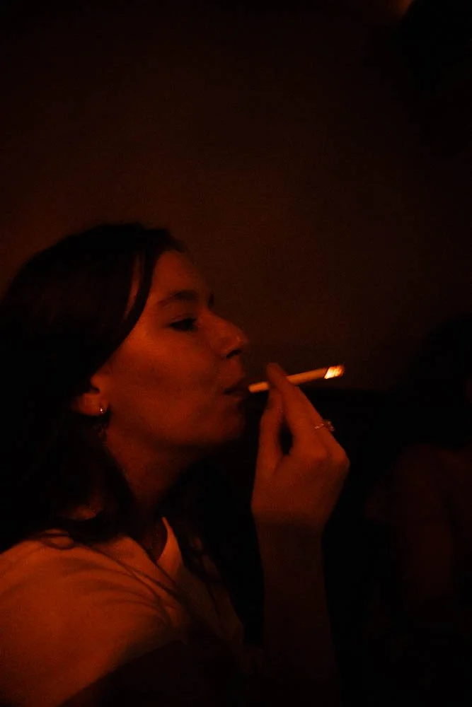 A woman smoking a cigarette in a dark environment.