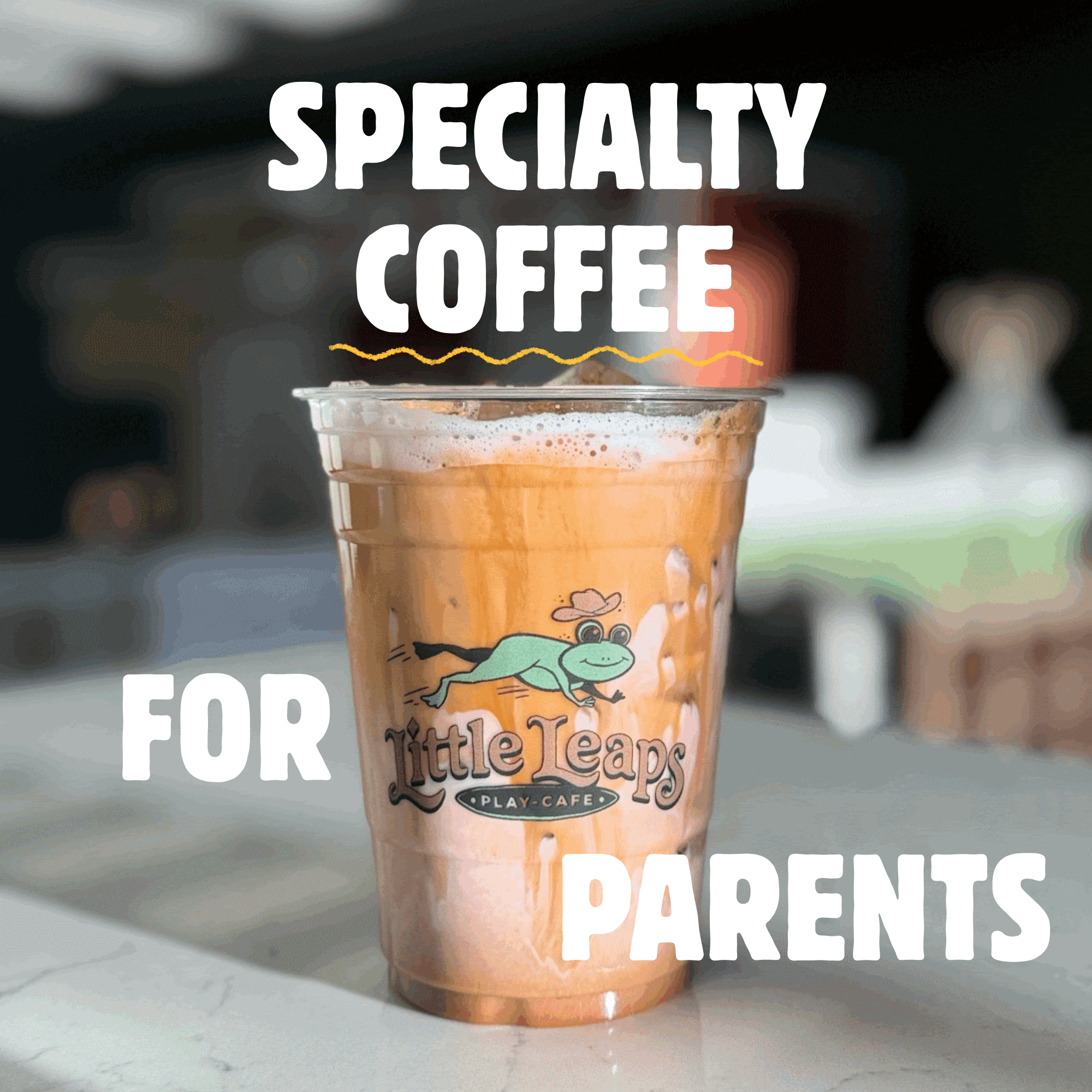 A plastic cup filled with a light brown iced coffee with foam on top and an illustration of a crocodile wearing a cowboy hat on the front, with text that reads "Play Cafe for Little Leaps".