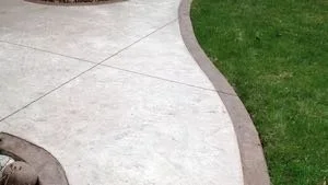Curved concrete sidewalk next to a grassy lawn.