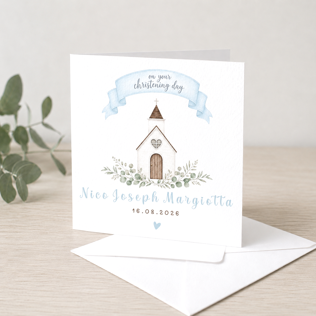A christening invitation card with a church illustration, greenery, and text including the name Nico Joseph Margiotta and the date 16.08.2026.