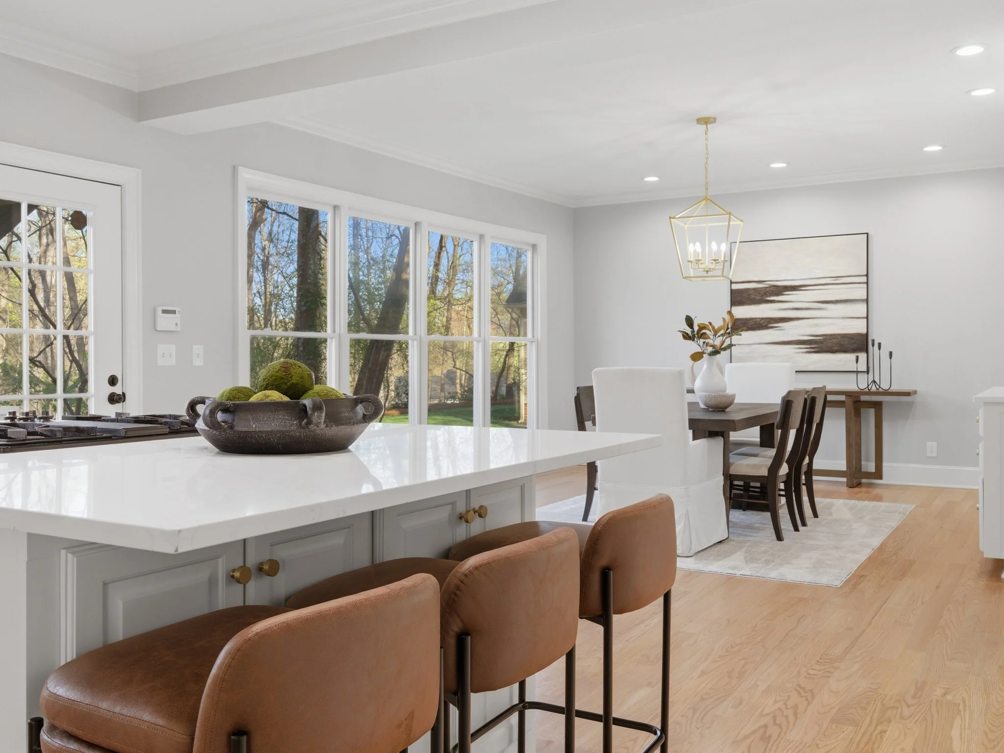 Staged kitchen island with leather stools open to dining room