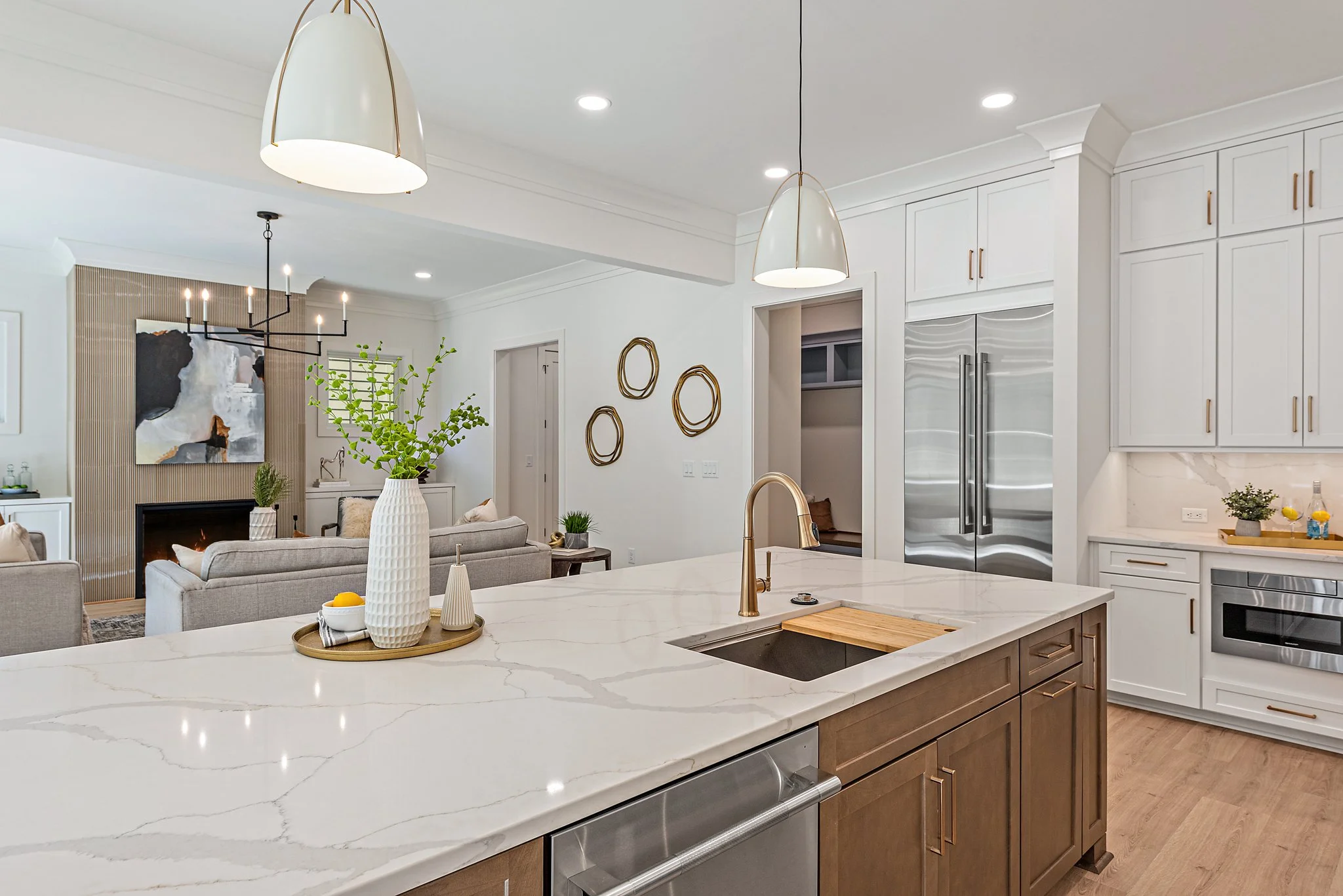 Staged kitchen with waterfall quartz island and brass fixtures