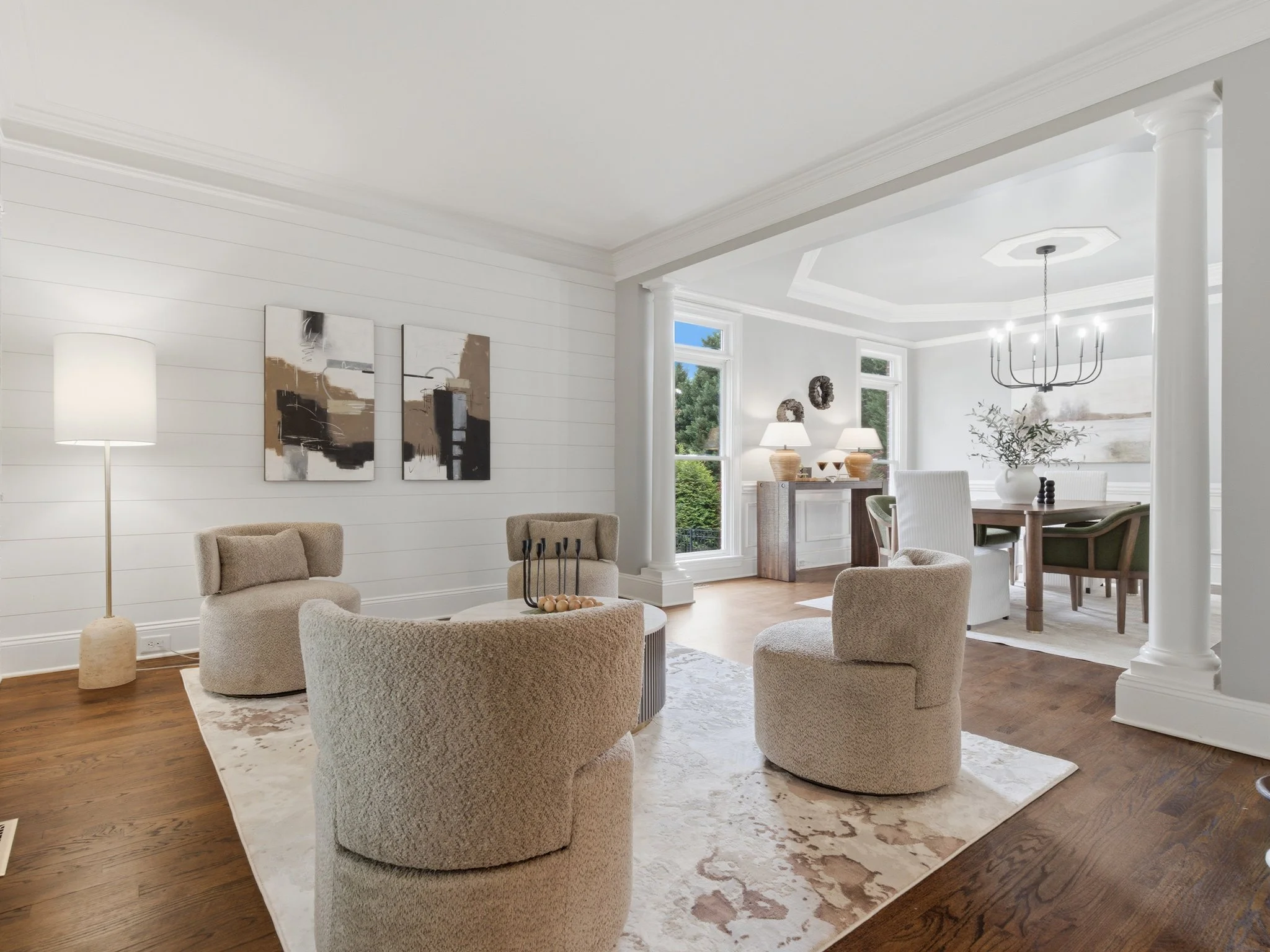 Staged sitting room with boucle swivel chairs open to dining room