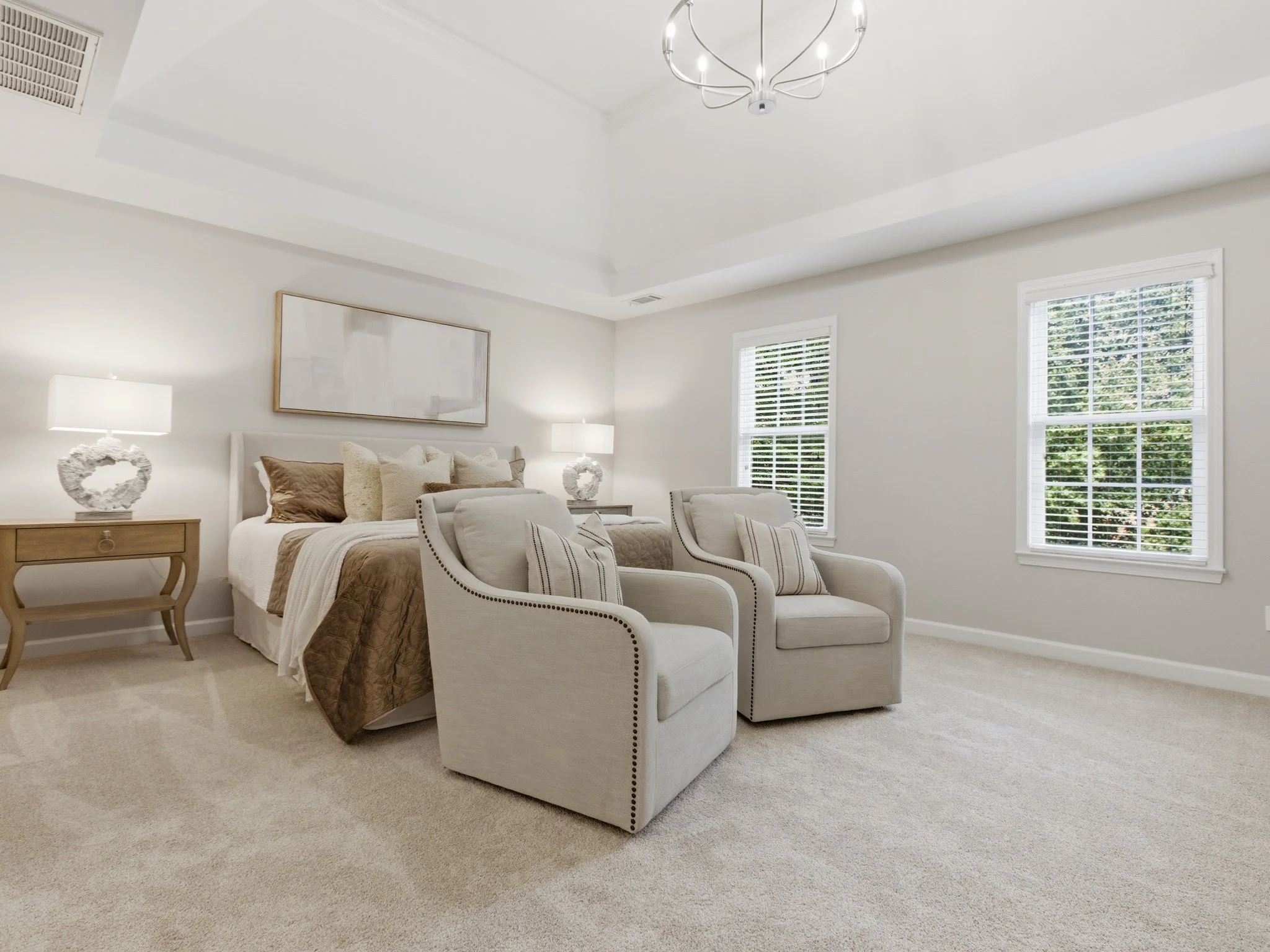 Staged primary bedroom with tray ceiling and accent chairs, Matthews NC
