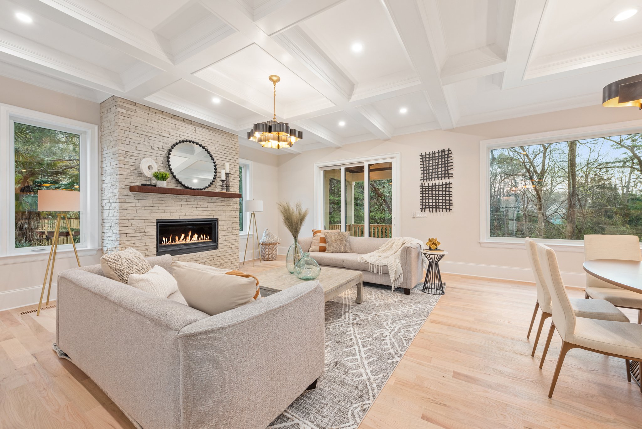 Staged living room with round mirror over stone fireplace
