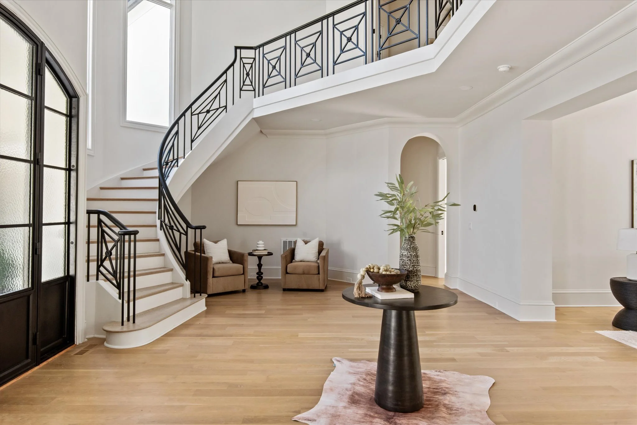 Staged two-story foyer with curved staircase and iron railing
